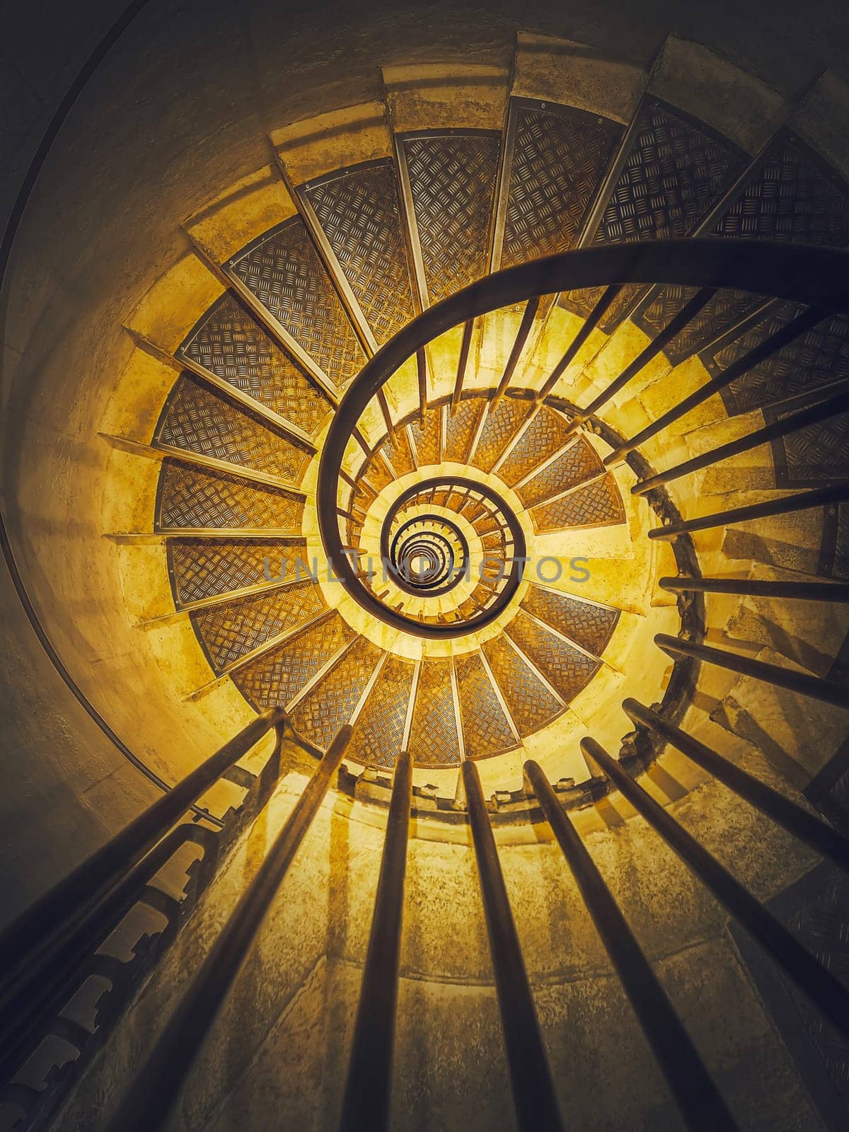 Spiral staircase abstract perspective with view downstairs to infinity swirl stairs in glowing yellow light