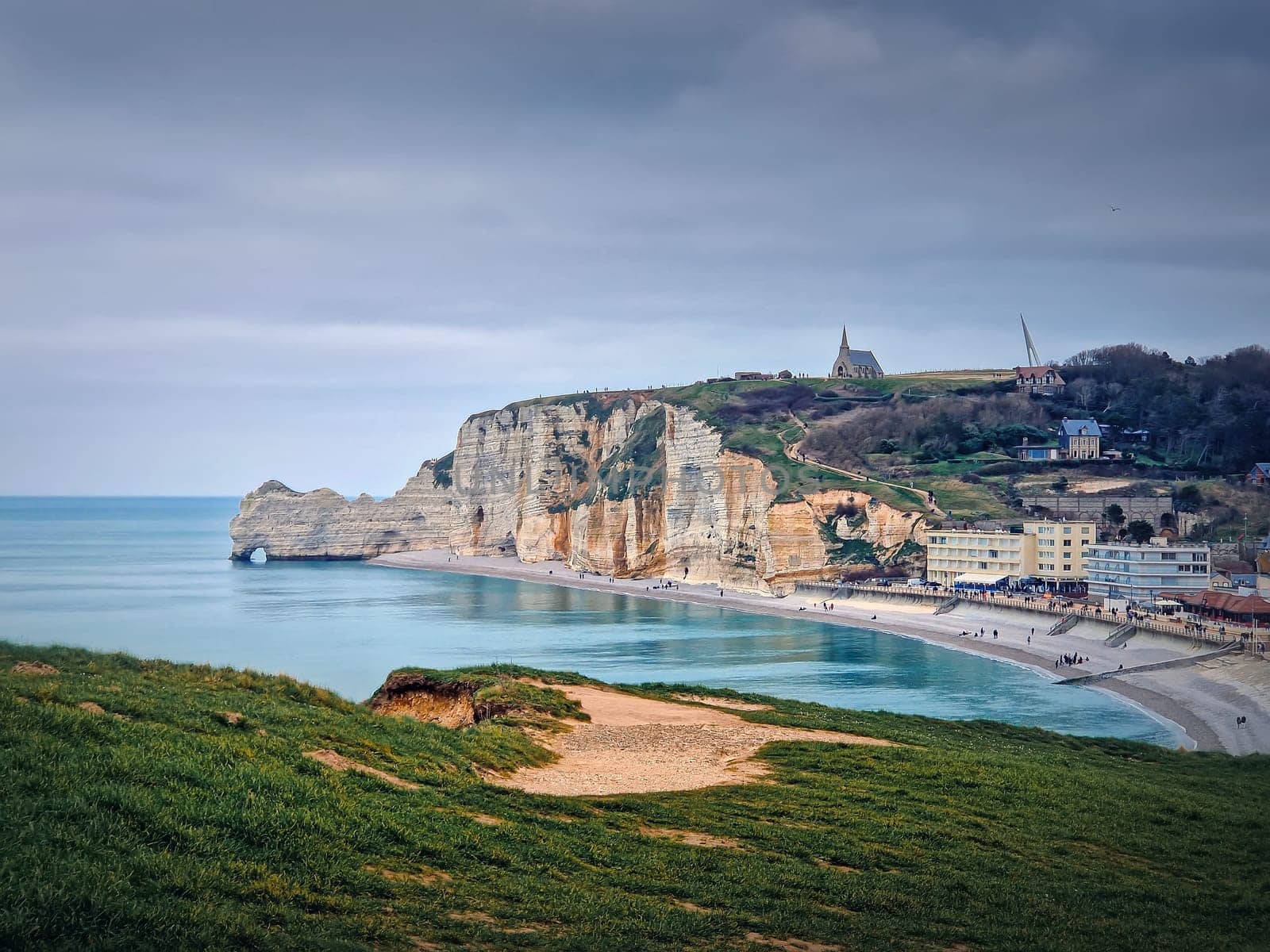 Sightseeing view to Etretat coastline with the famous Notre-Dame de la Garde chapel on the Amont cliff. Seashore washed by Atlantic ocean waters, Normandy, France by psychoshadow