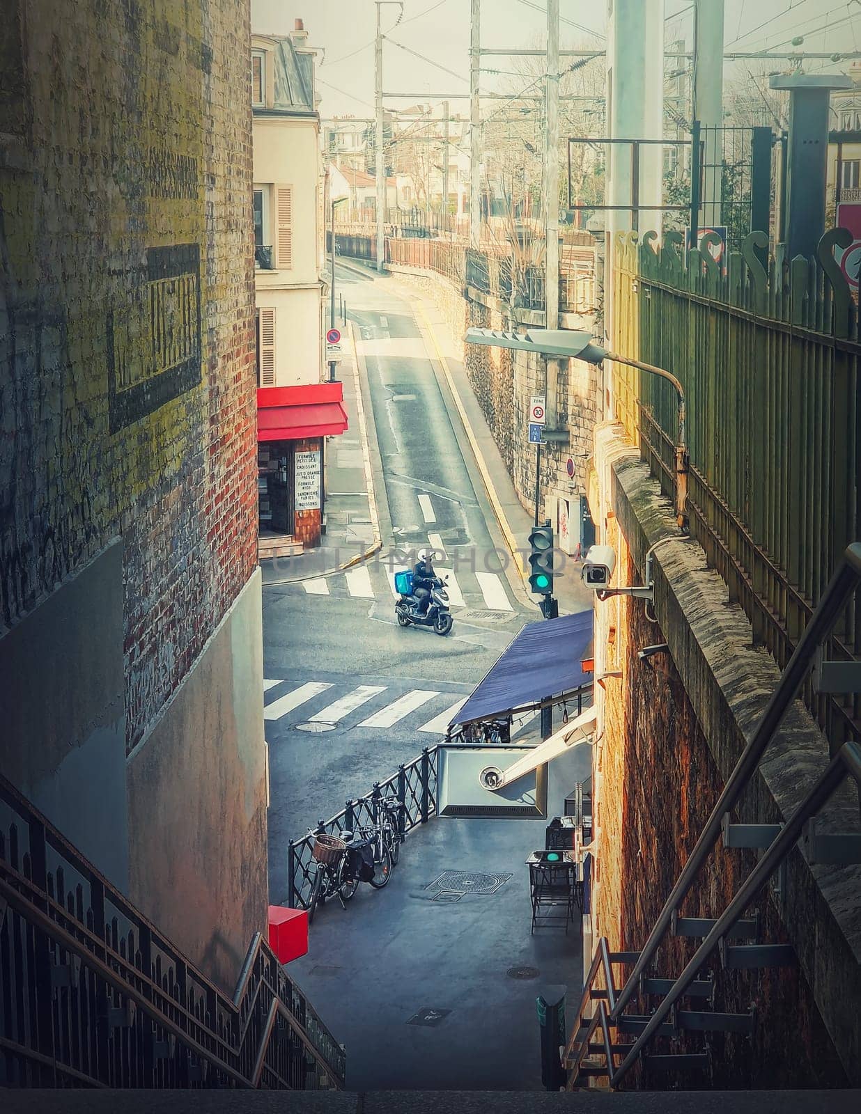 Delivery man or courier driving a motorcycle in the crossroad of city, Asnieres sur Seine, a Paris suburb town, France  by psychoshadow