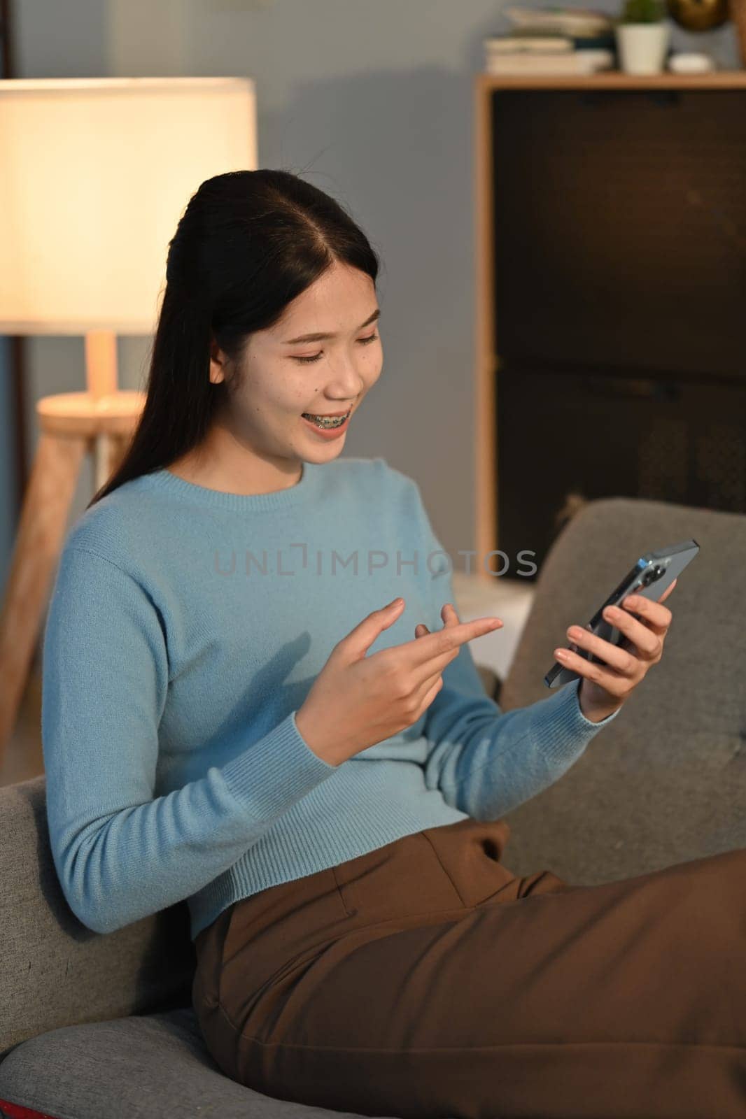 Shot of young woman using her digital tablet while sitting on sofa at home. by prathanchorruangsak