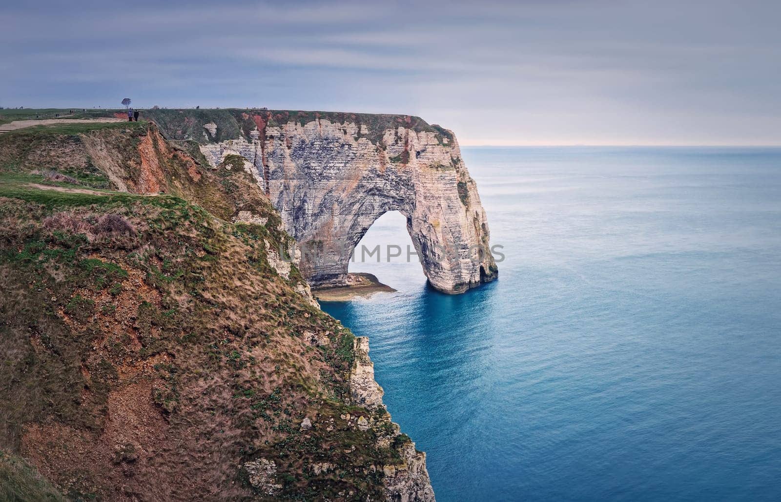 Sightseeing view to the Porte d'Aval natural arch cliff washed by Atlantic ocean waters at Etretat, Normandy, France. Beautiful coastline scenery with famous Falaise d'Aval by psychoshadow