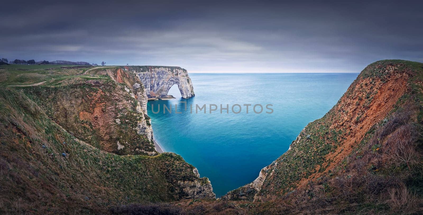 Sightseeing panoramic view to the Porte d'Aval natural arch cliff washed by Atlantic ocean waters at Etretat, Normandy, France. Beautiful coastline scenery with famous Falaise d'Aval by psychoshadow