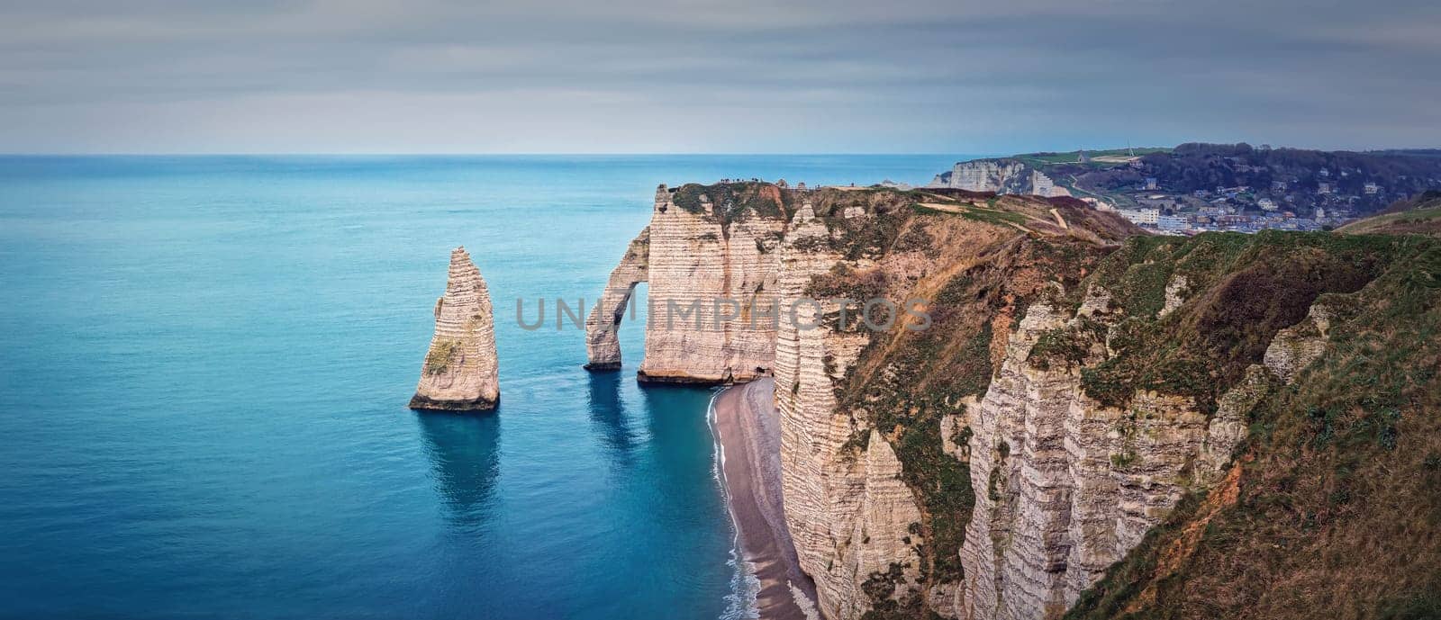 Panoramic view to the famous rock Aiguille of Etretat in Normandy, France. Limestone cliffs Falaise d'Aval washed by La Manche channel waters. Beautiful coastline panorama by psychoshadow