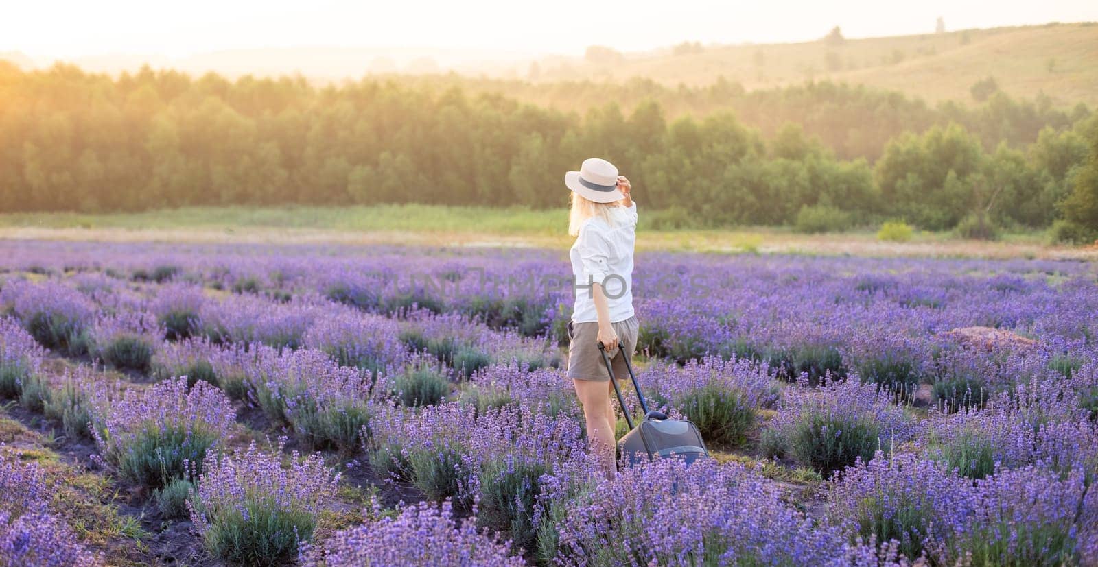 woman with suitcase in lavender field. by Andelov13