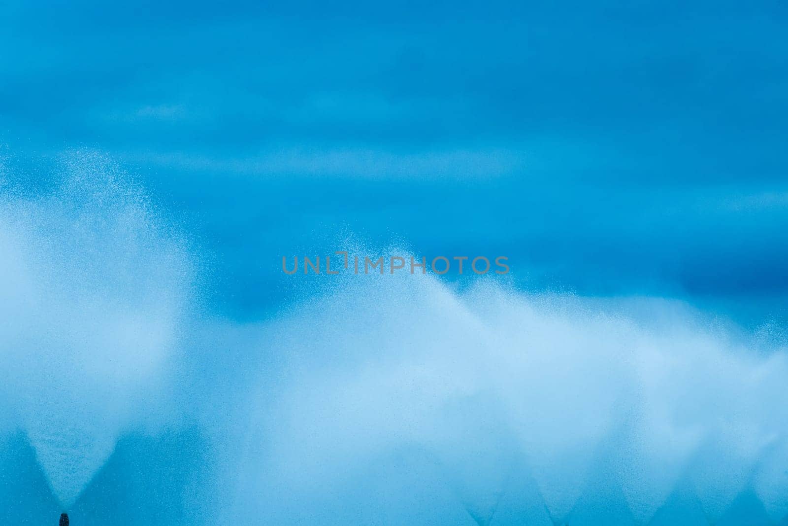 Splashes of water fountain movement of liquid flow against the dark blue sky background.