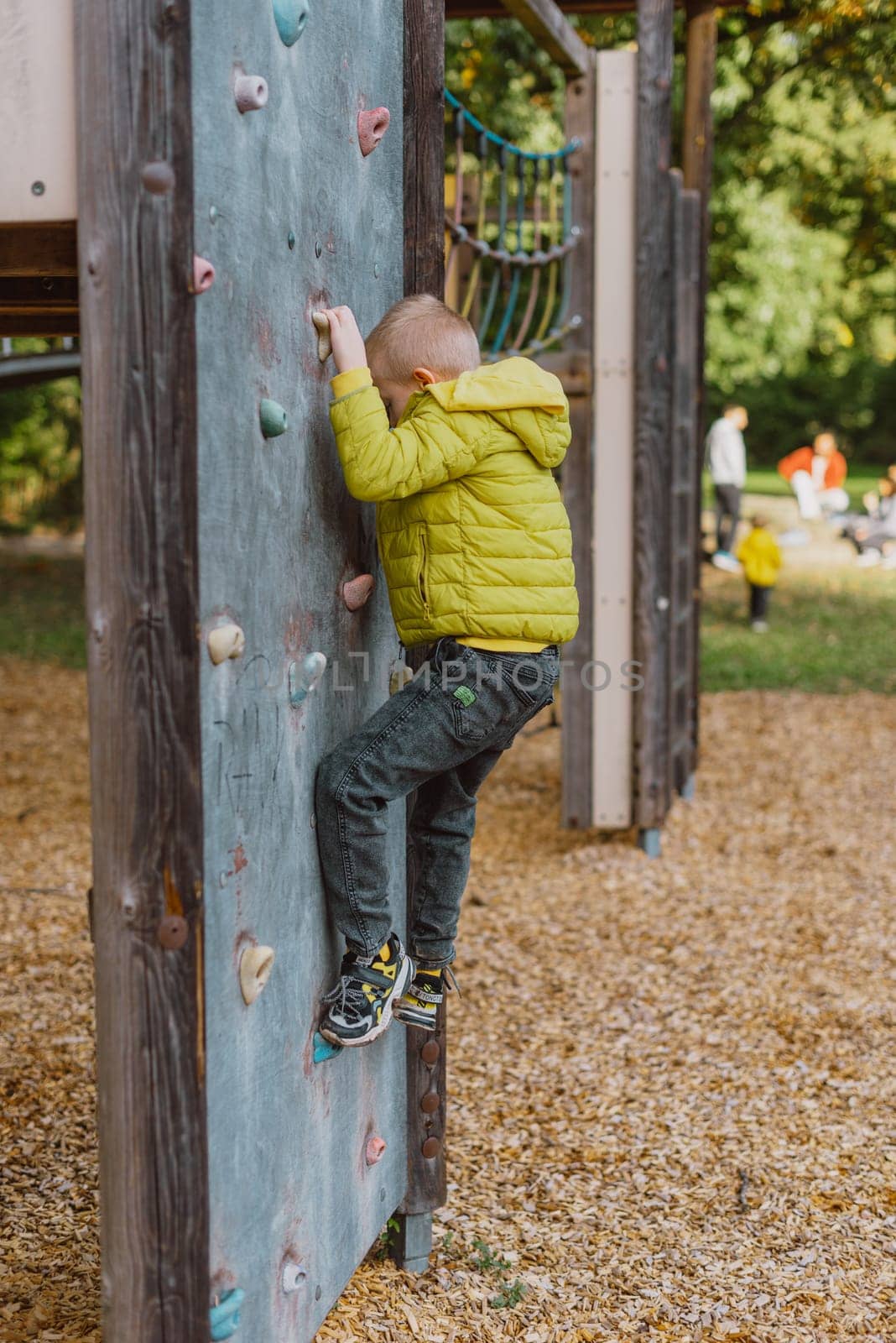 Boy At The Climbing Wall Without A Helmet, Danger At The Climbing Wall. Little Boy Climbing A Rock Wall Indoor by Andrii_Ko