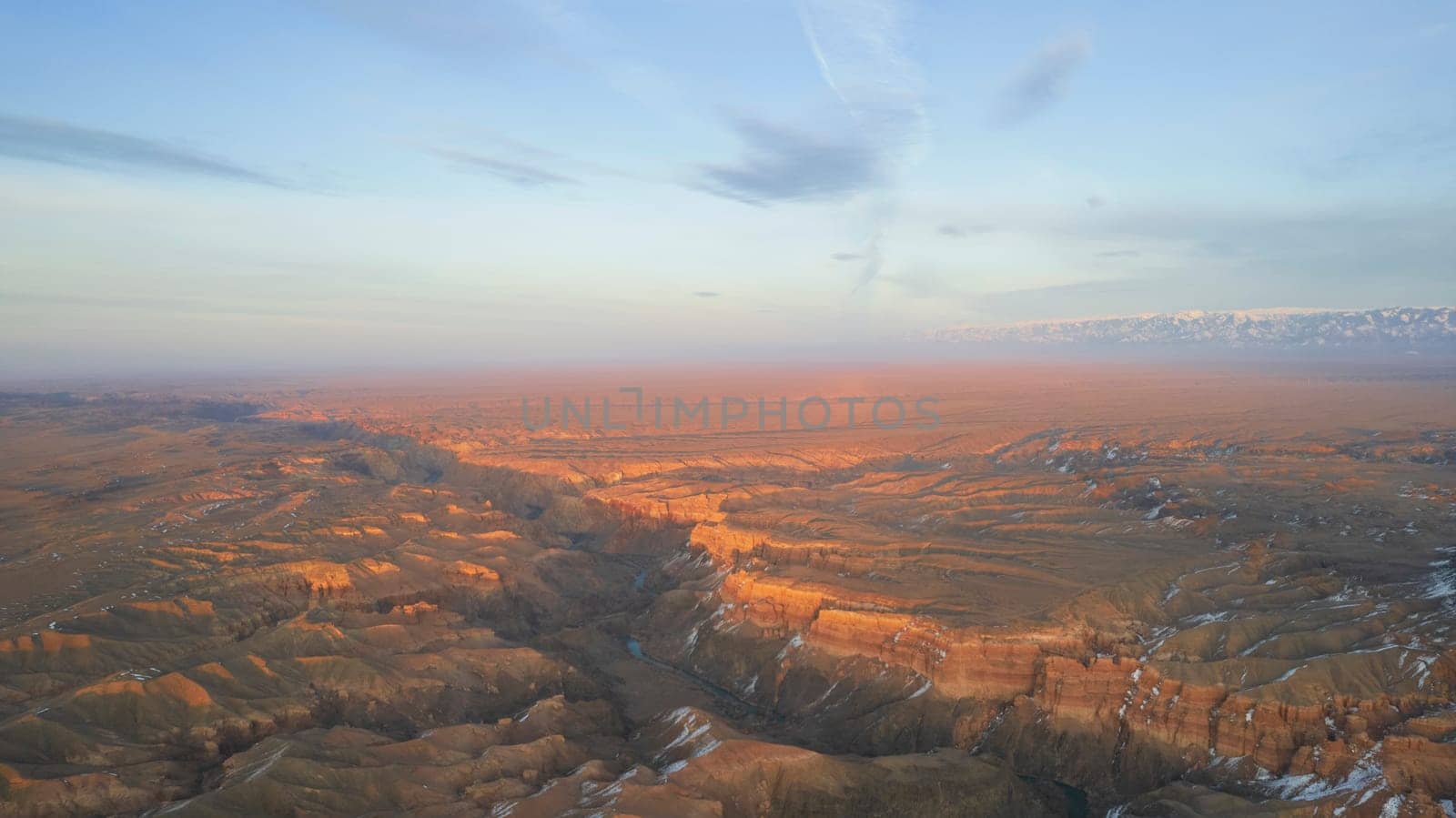 Charyn Grand Canyon with orange rock walls. Aerial view from the drone of the steep canyon walls, cracks and tunnels. There is snow in places. Beautiful sunset and sunrise. Brother of the Grand Canyon