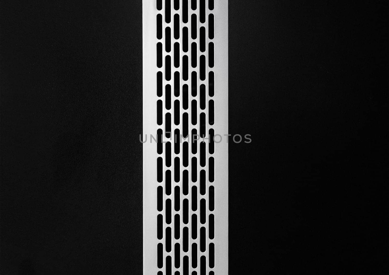 Ventilation air system modern ventilation cooling grille mounted in a black wall, close-up.