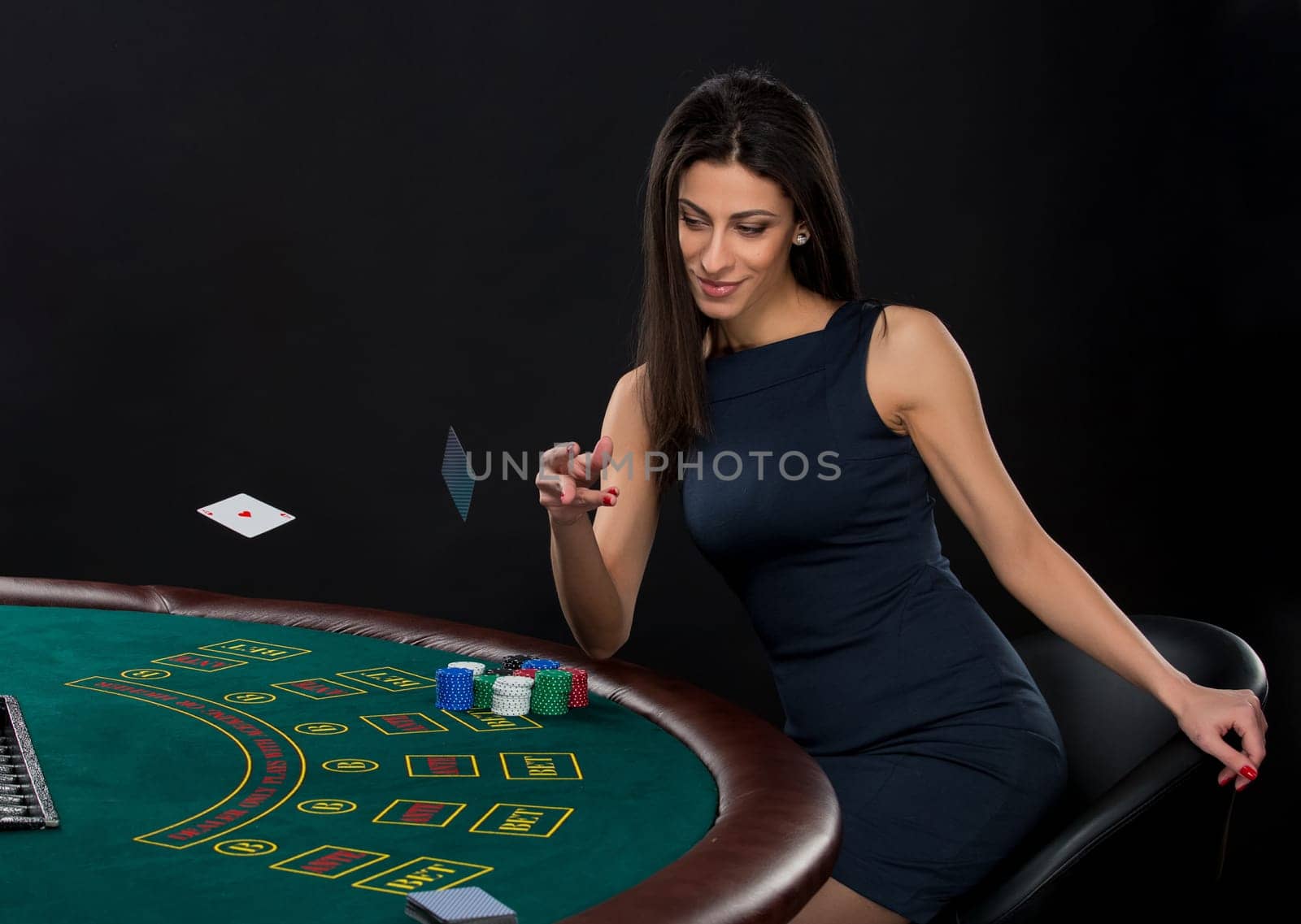 sexy woman with poker cards and chips. Female player in a beautiful black dress, throws a card. Two aces