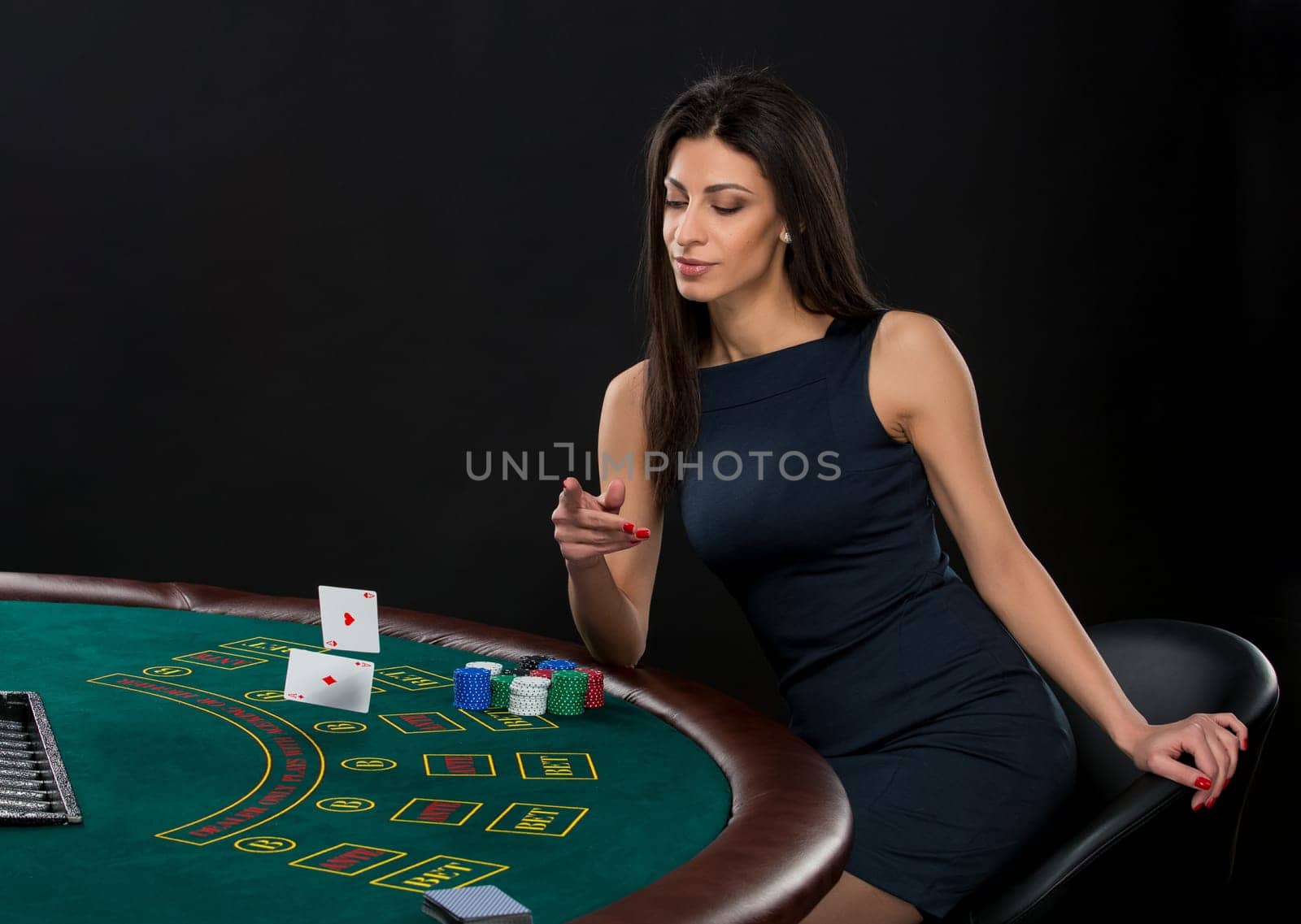 sexy woman with poker cards and chips. Female player in a beautiful black dress, throws a card. Two aces