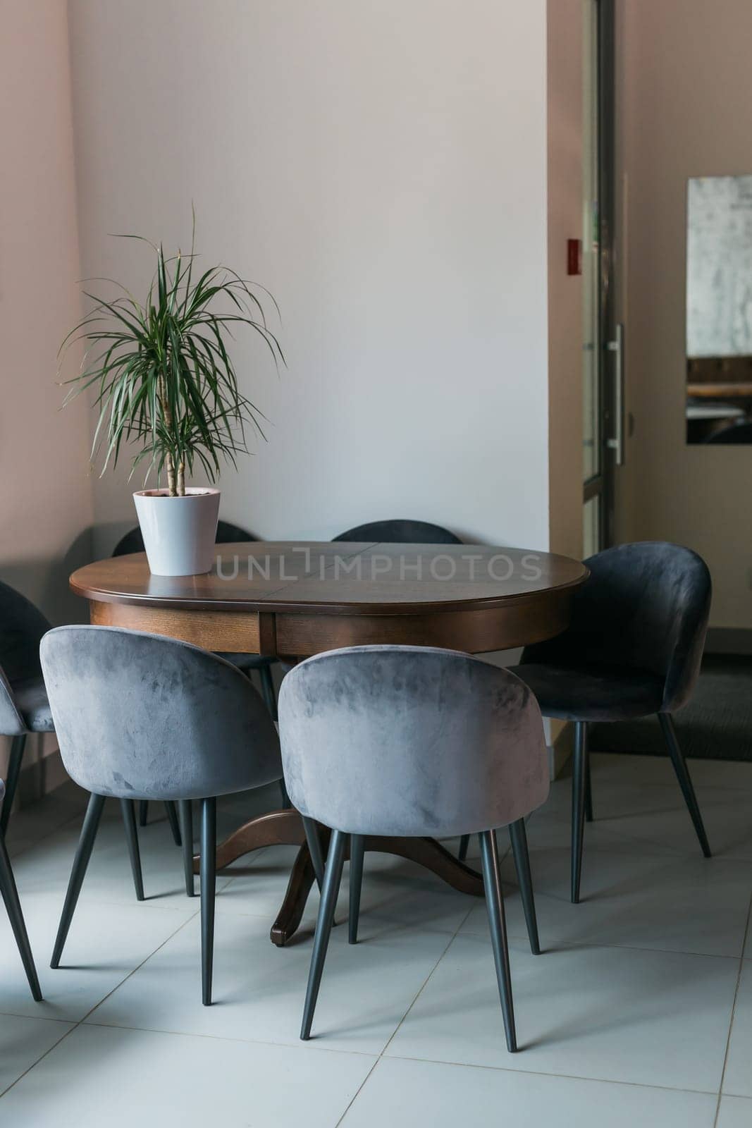 Grey chairs at wooden table and green plant in pot in minimalist cafe interior with poster and window by Satura86