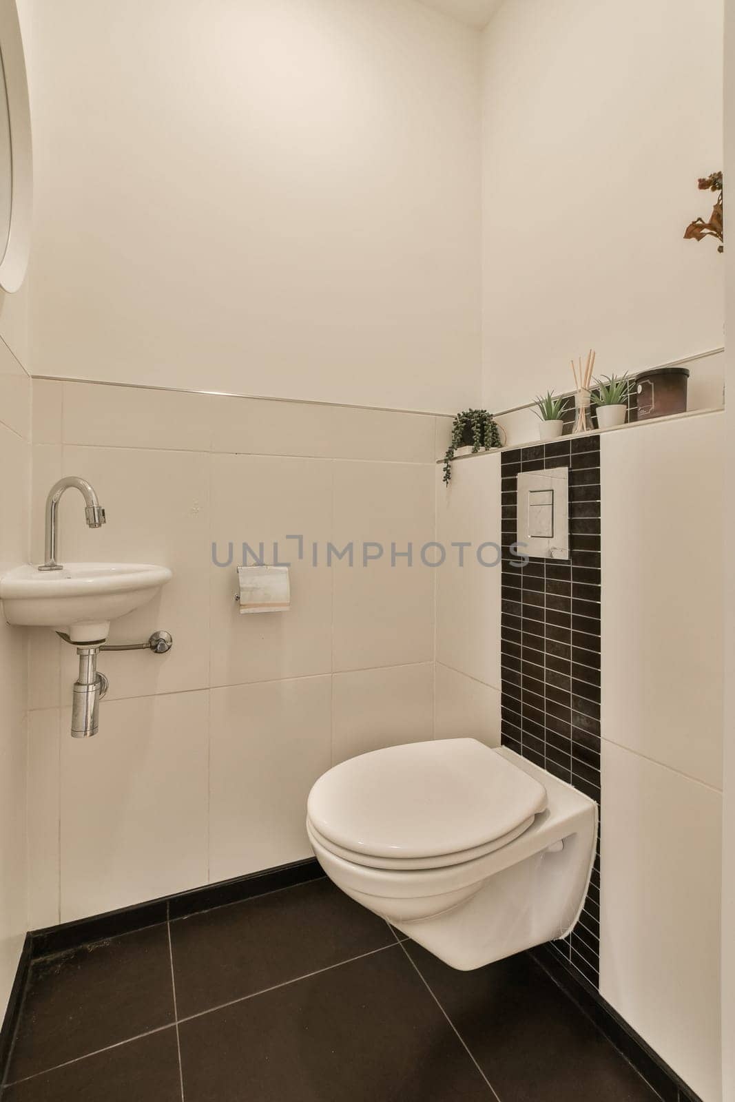 a white bathroom with black tile flooring and wall mounted toilet in the corner, there is a mirror on the wall