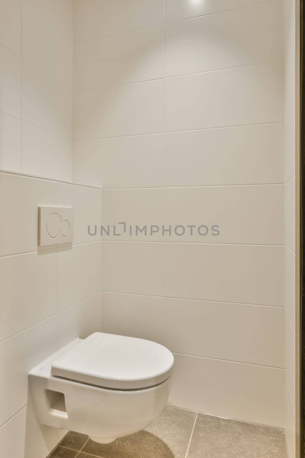 a white toilet in a bathroom with white tiles by casamedia