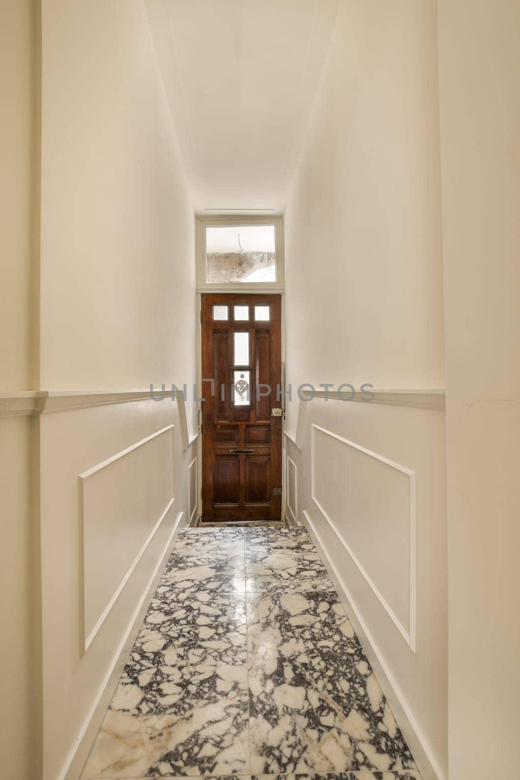 a hallway with white walls and a wooden door by casamedia