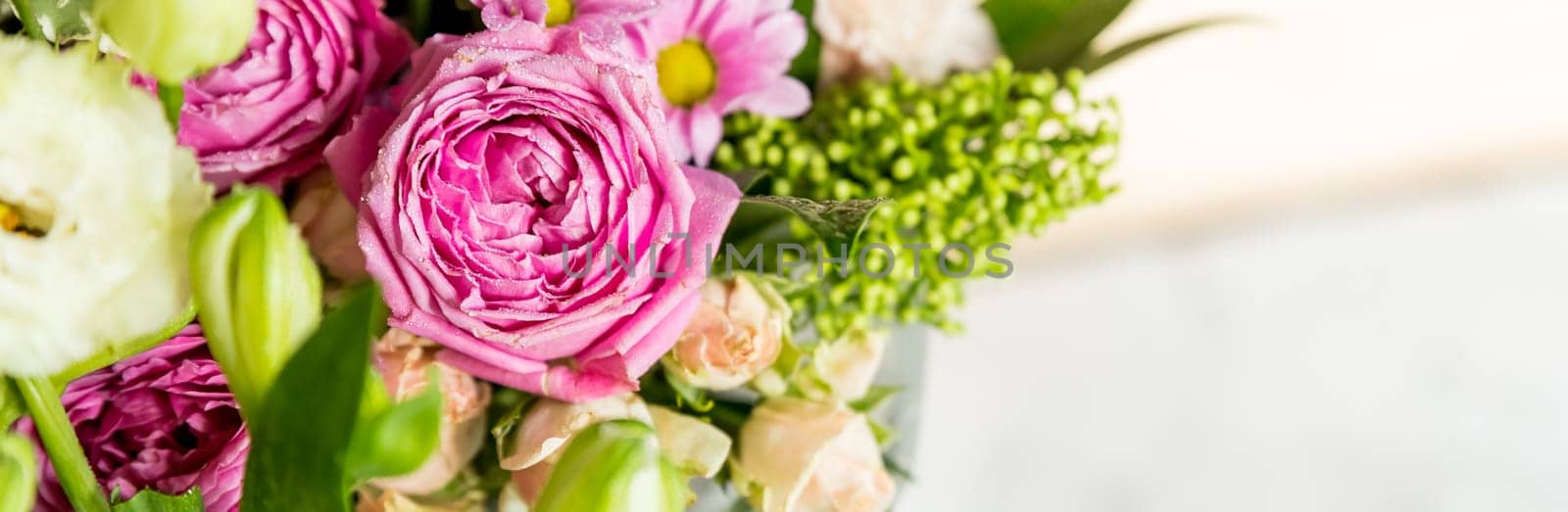 two bouquets of roses, daisies, lisianthus, chrysanthemums, unopened buds on a plank table and a background of pink silk fabric with pleats.