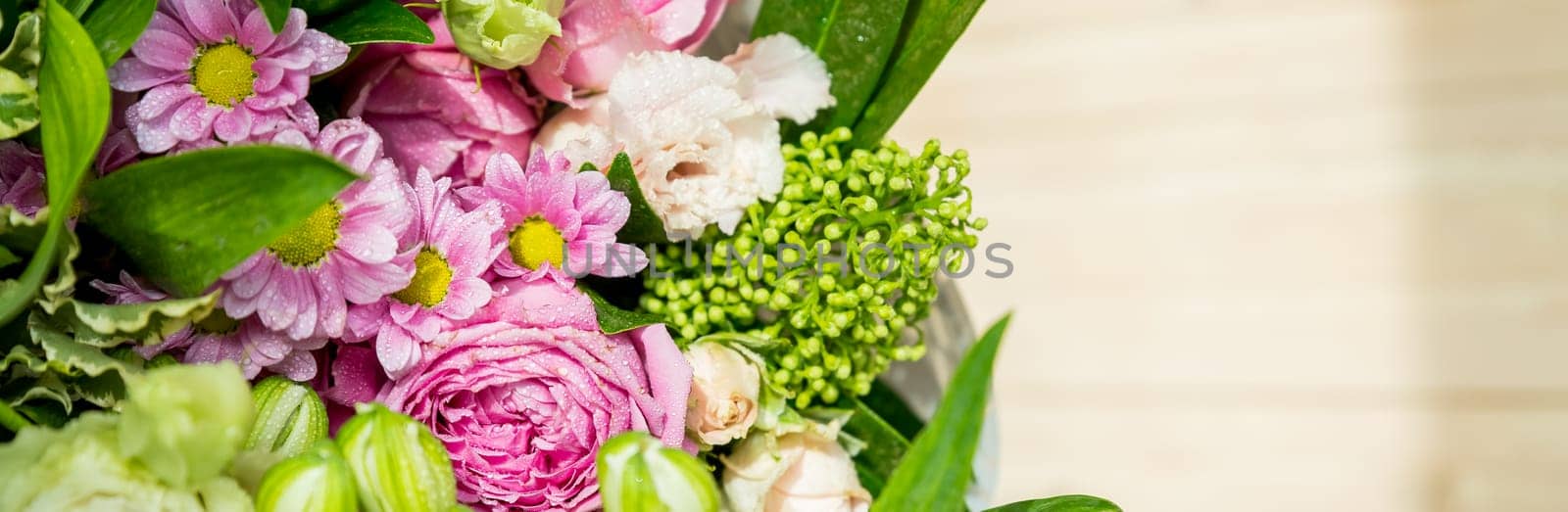 two bouquets of roses, daisies, lisianthus, chrysanthemums, unopened buds on a plank table and a background of pink silk fabric with pleats.