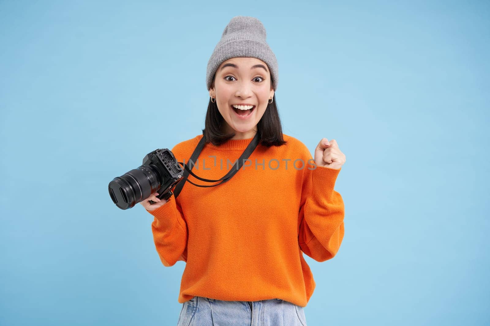 Passionate asian girl photographer, taking pictures on her digital camera, capturing moments outdoors, shooting photos, blue background.