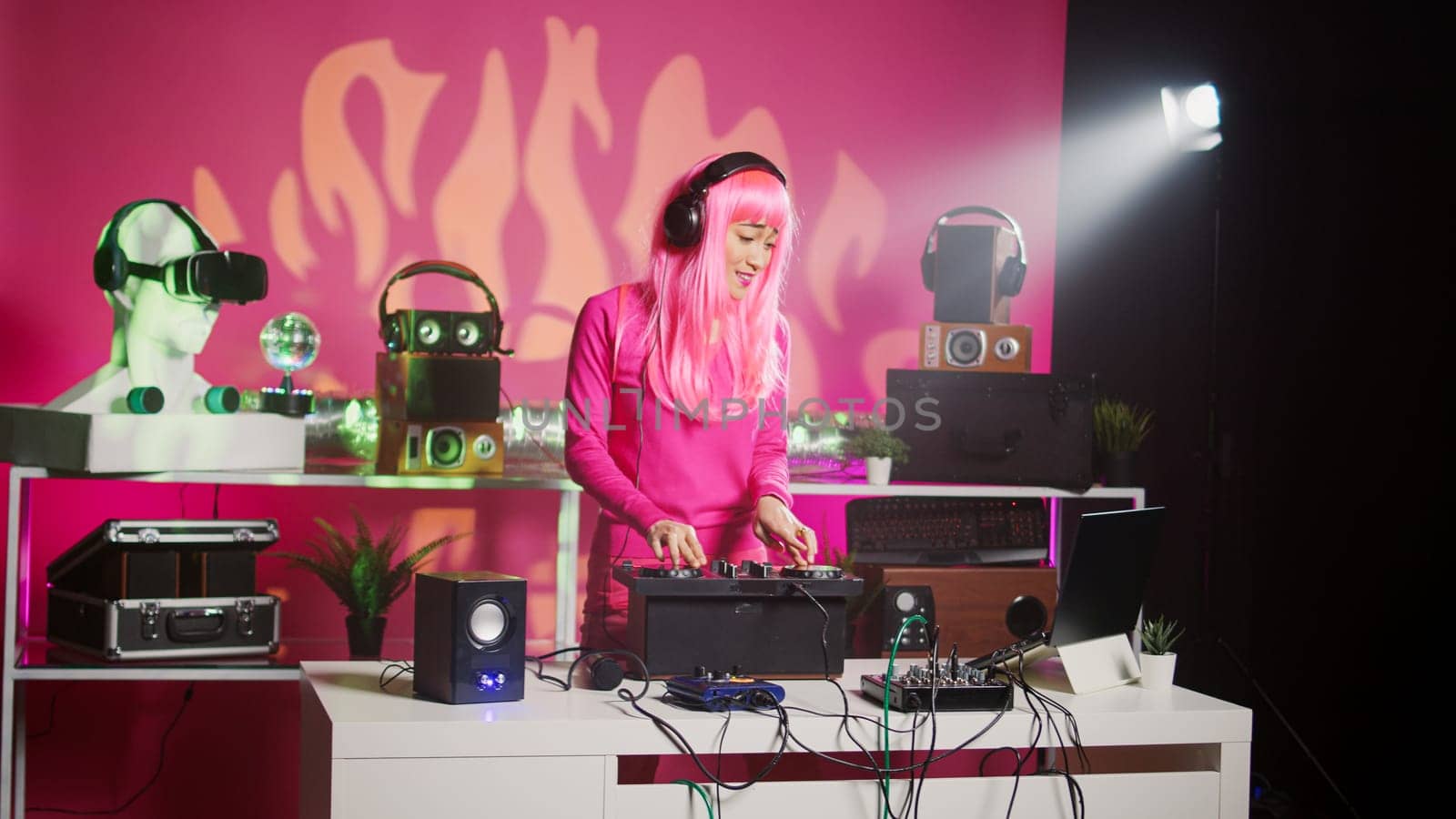 Smiling dj artist wearing headphones during performance, mixing eletronic sound with techno playing music at professional mixer console. Musician enjoying partying at night in club