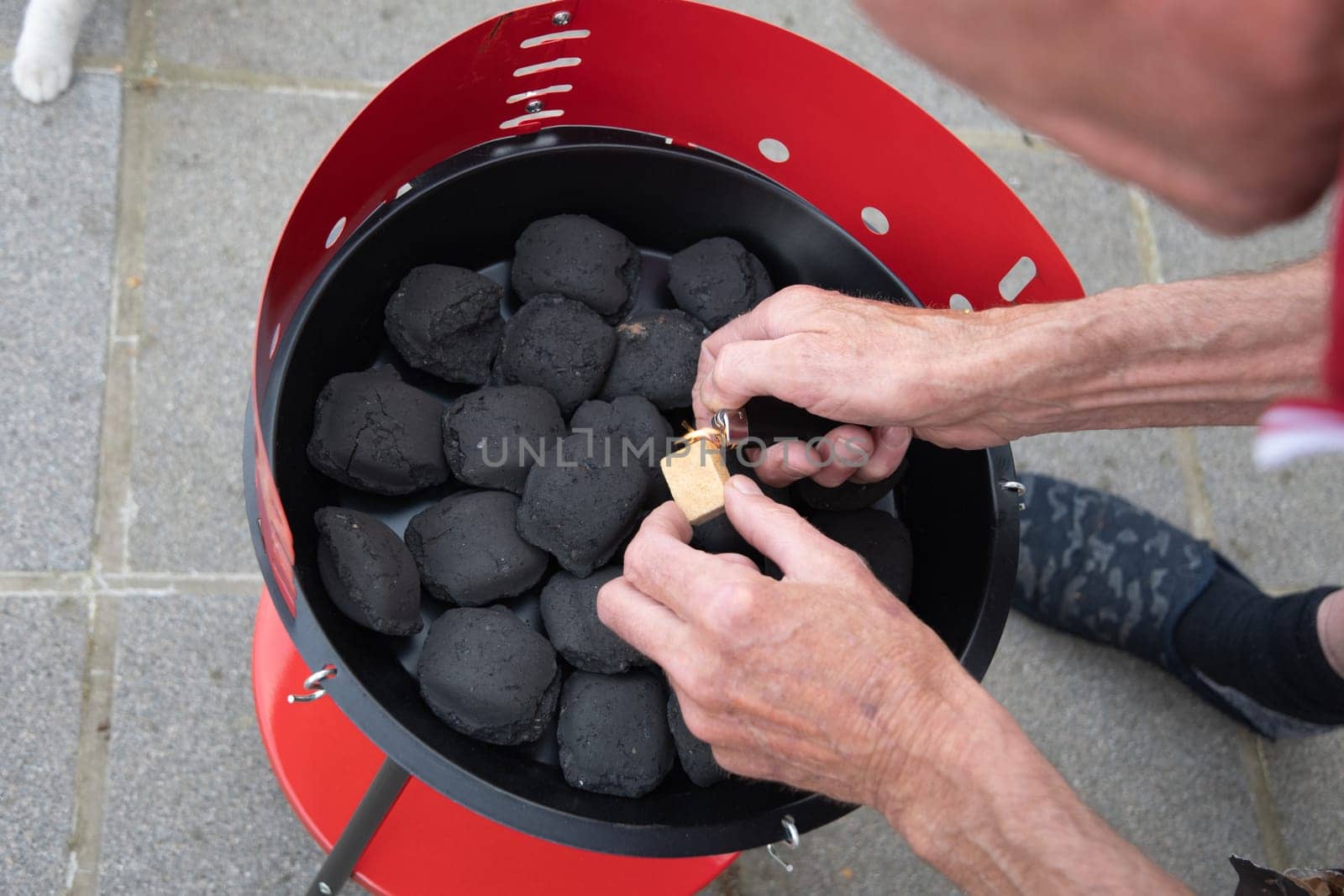 a man lights a fire with a lighter special charcoals for a barbecue a barbecue house on the terrace prepares a place for a barbecue. High quality photo