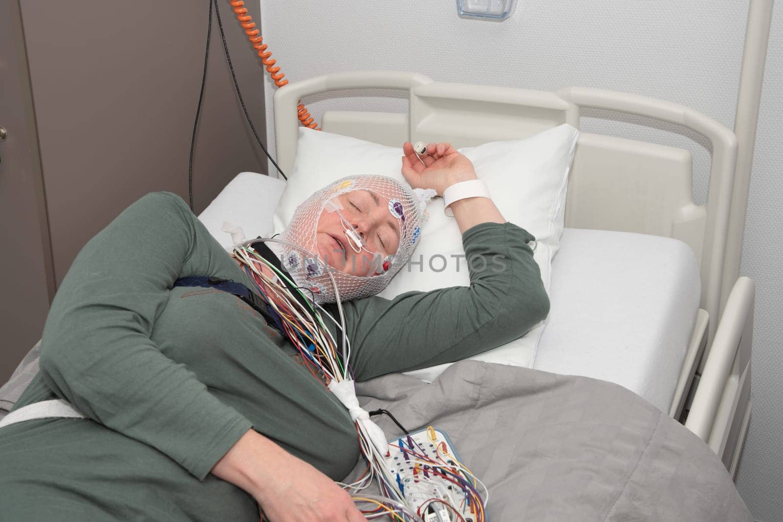 Middle aged woman measuring brain waves, examining polysomnography in sleep lab by KaterinaDalemans