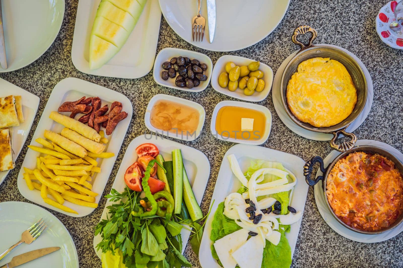 Turkish breakfast table. Pastries. Vegetables. Olives. Cheeses, fried eggs. Jams, tea in copper pot and tulip glasses. Wide composition.