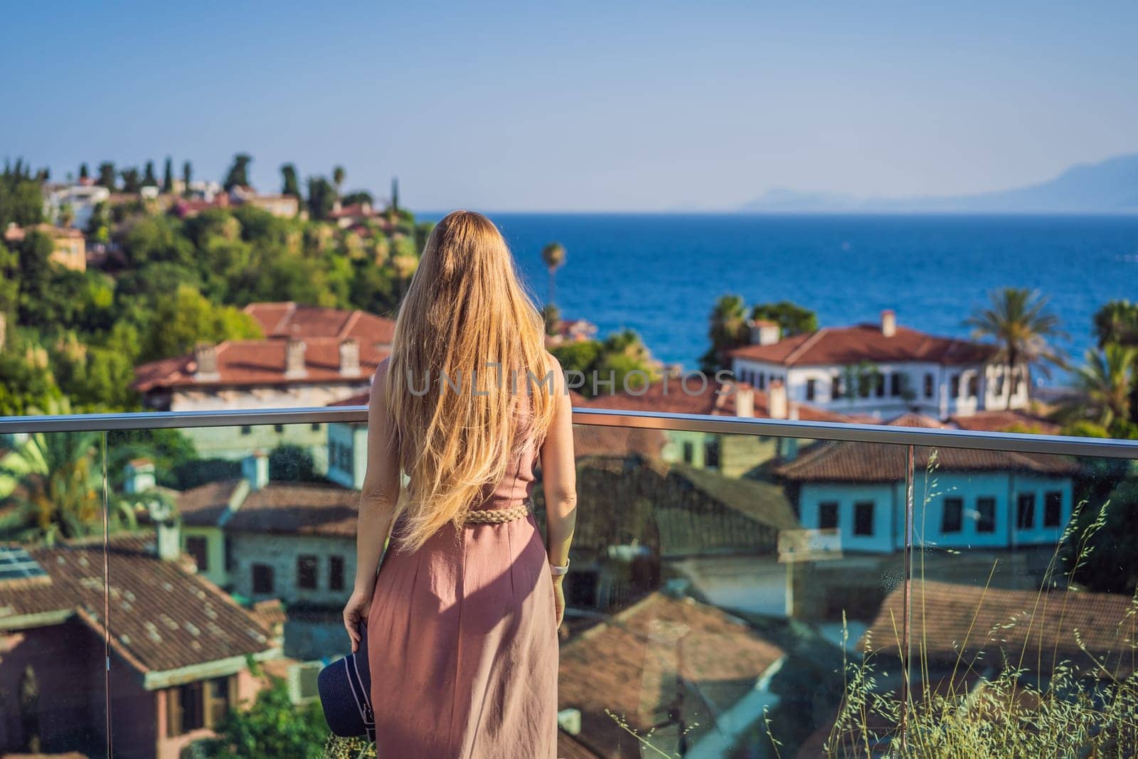 Woman tourist in Old town Kaleici in Antalya. Turkiye. Panoramic view of Antalya Old Town port, Taurus mountains and Mediterrranean Sea, Turkey.