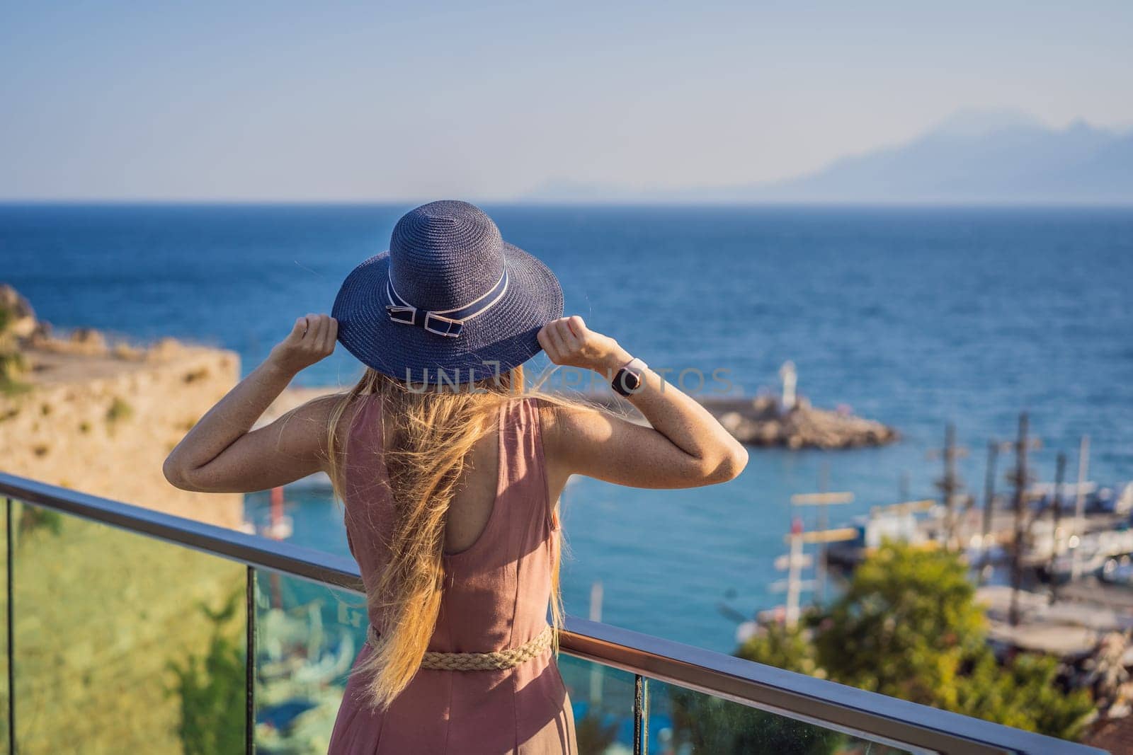 Woman tourist in Old town Kaleici in Antalya. Turkiye. Panoramic view of Antalya Old Town port, Taurus mountains and Mediterrranean Sea, Turkey.