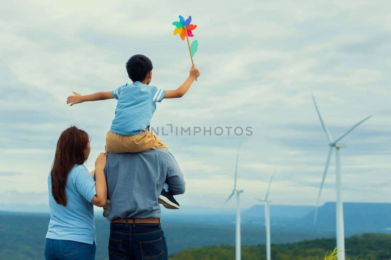Progressive happy family enjoy their time at wind farm for green energy concept. by biancoblue