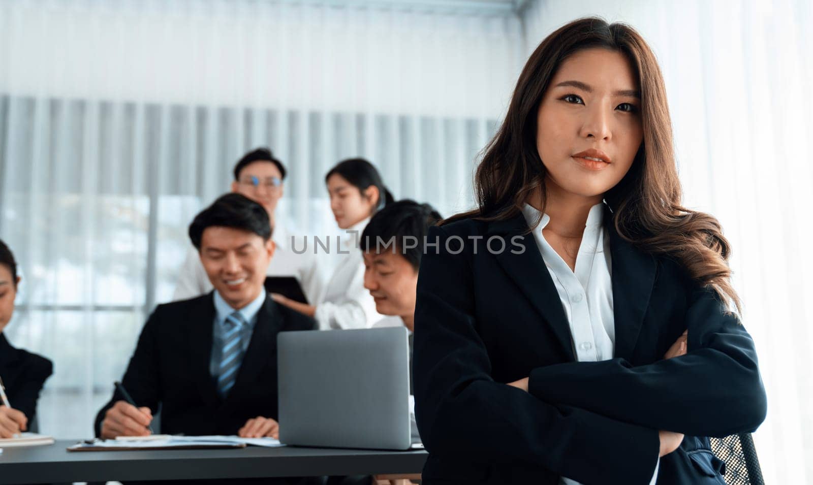 Focus portrait of asian female manger with blurred colleague figures in harmony. by biancoblue