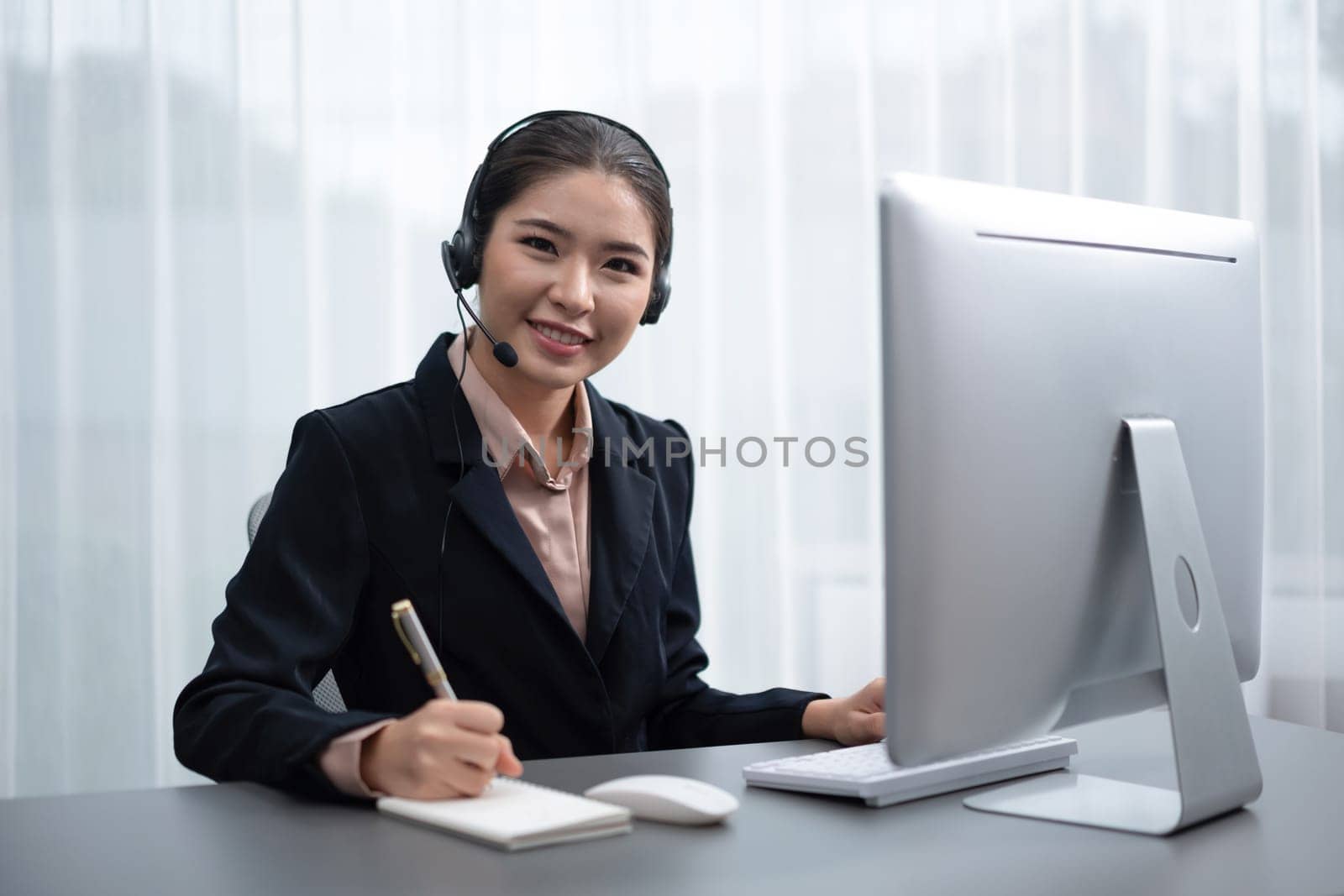 Enthusiastic asian call center with headset on her workplace portrait. by biancoblue