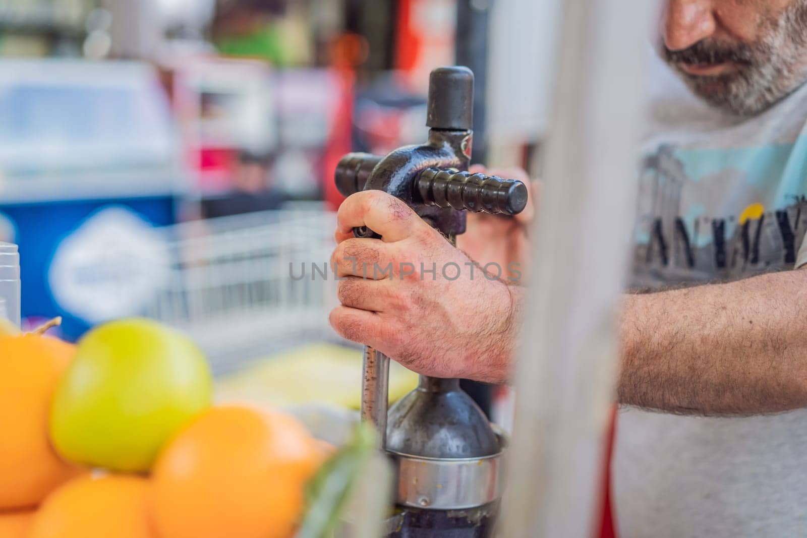 Freshly squeezed juice, street food. Man's hands making orange juice.