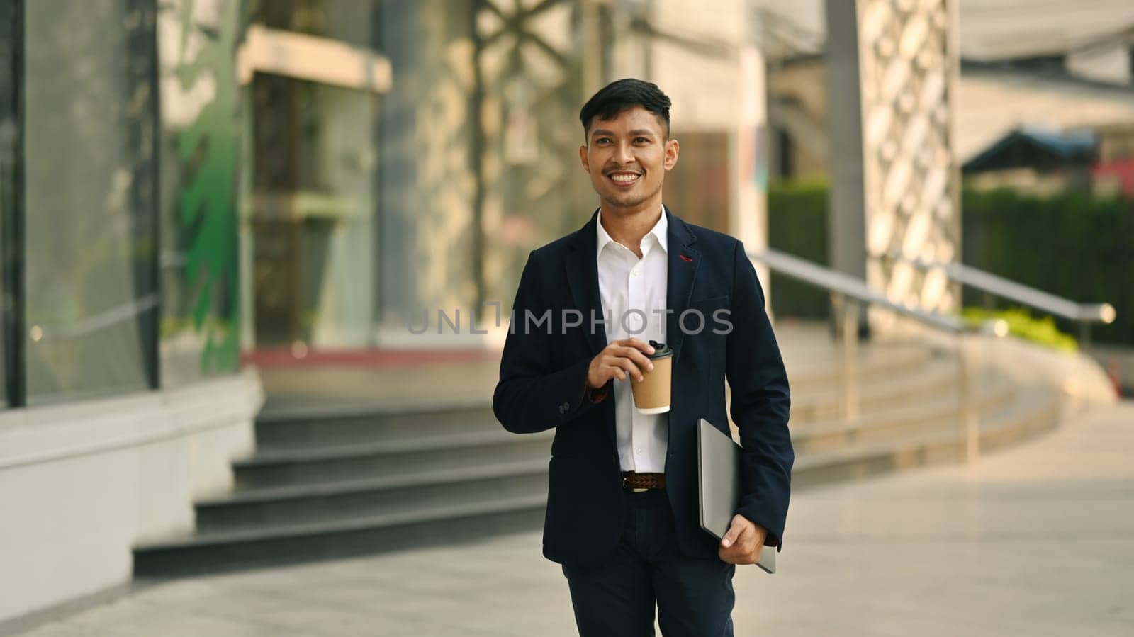 Shot of comfident young businesswoman holding takeaway coffee cup walking outdoors in business district.