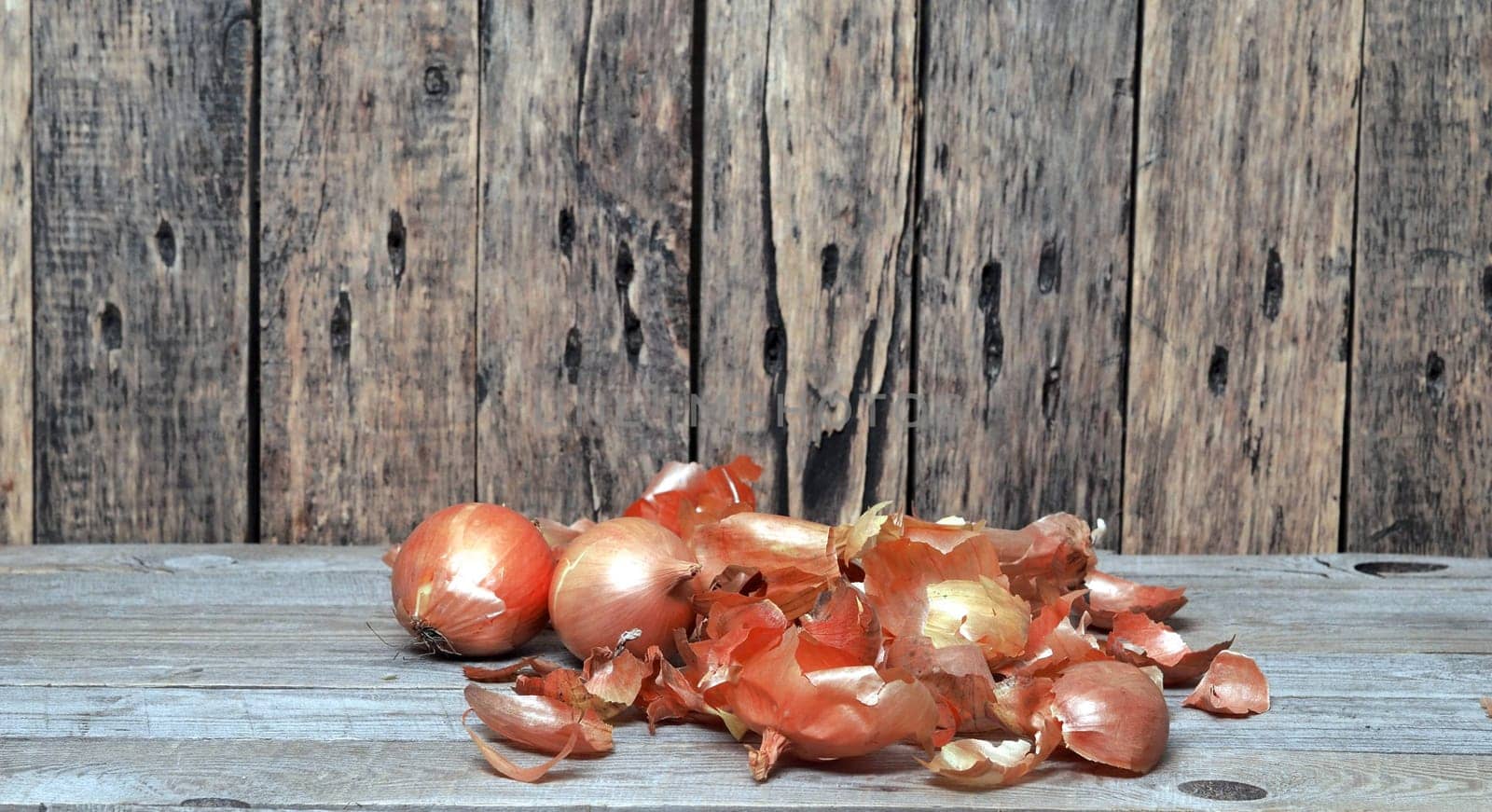 Food background with onion and husk on wooden natural background.The concept of onion health benefits for people.