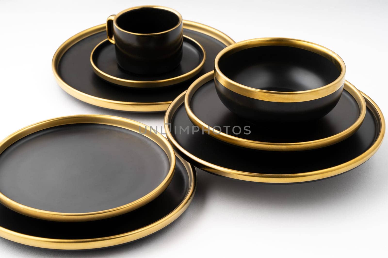 A set of black and golden ceramic plates and cup on a white background