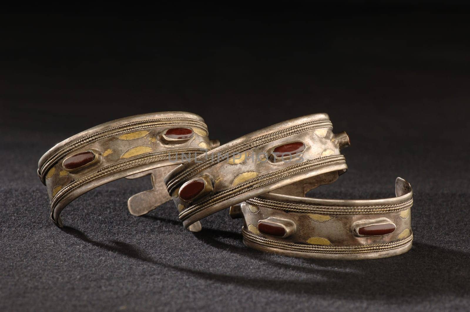 The antique, elegant bracelets with engraving and precious red stones isolated on a black background