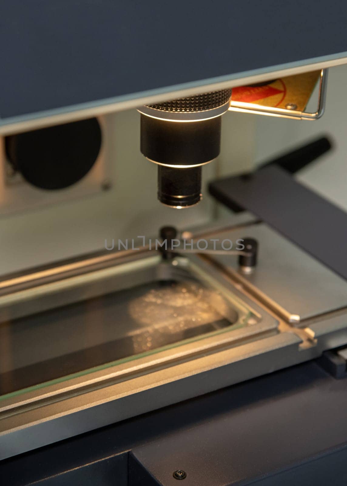 A vertical closeup shot of an illuminated microscope at a medical production warehouse by A_Karim