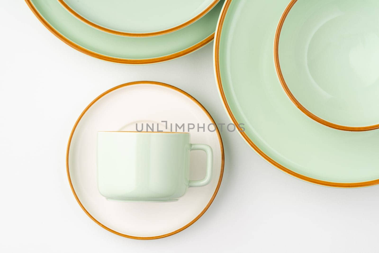 A set of white and pastel green ceramic tableware with orange outlines