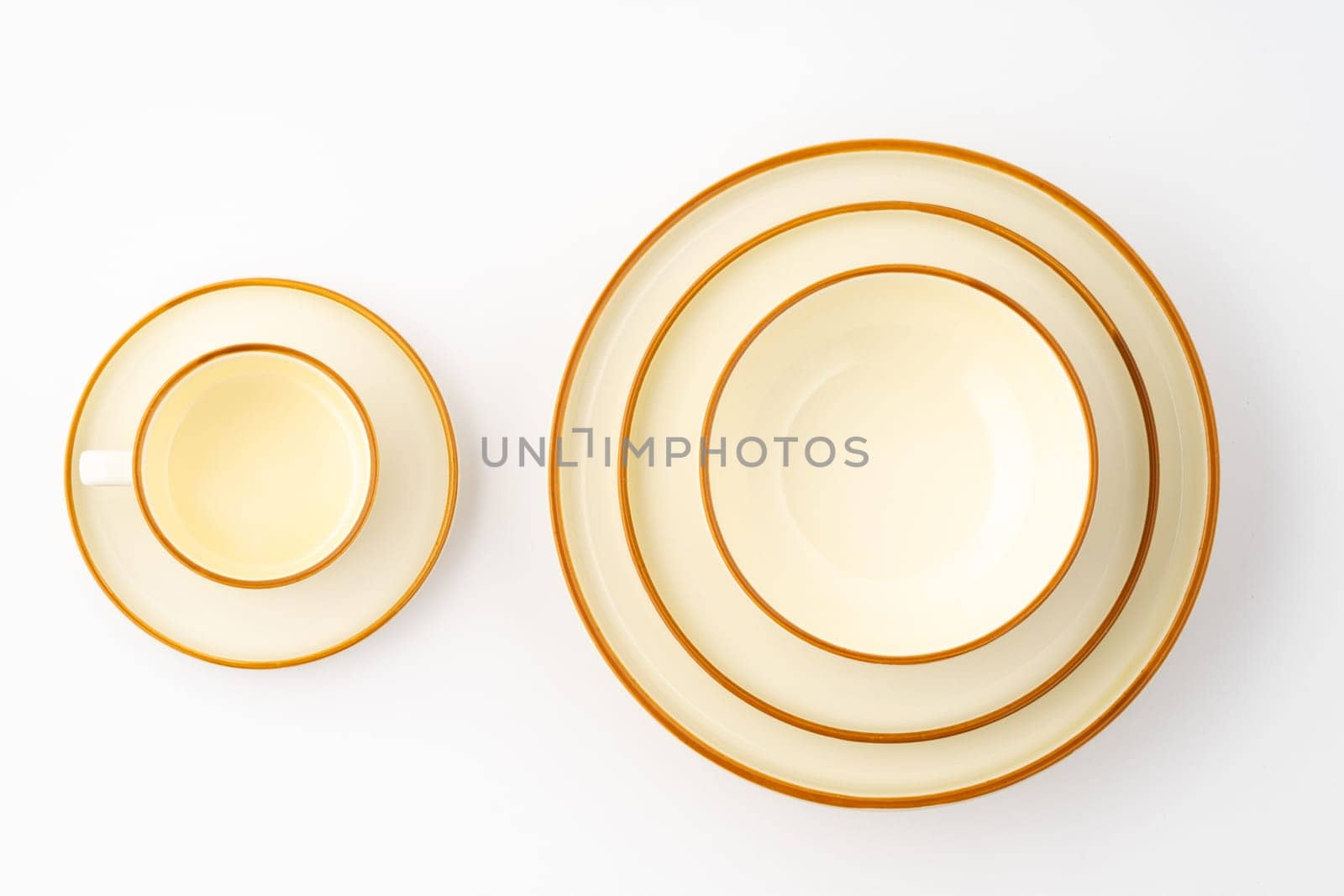 A set of white and brown ceramic plate and cup on a white background. Top view by A_Karim