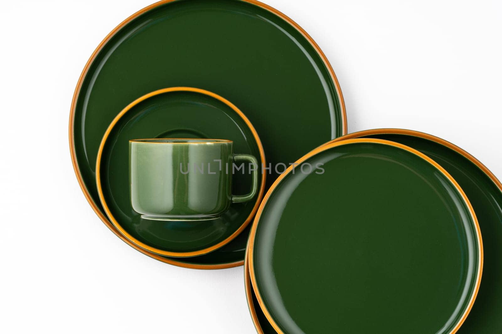 A set of green ceramic plates and coffee mug on a white background