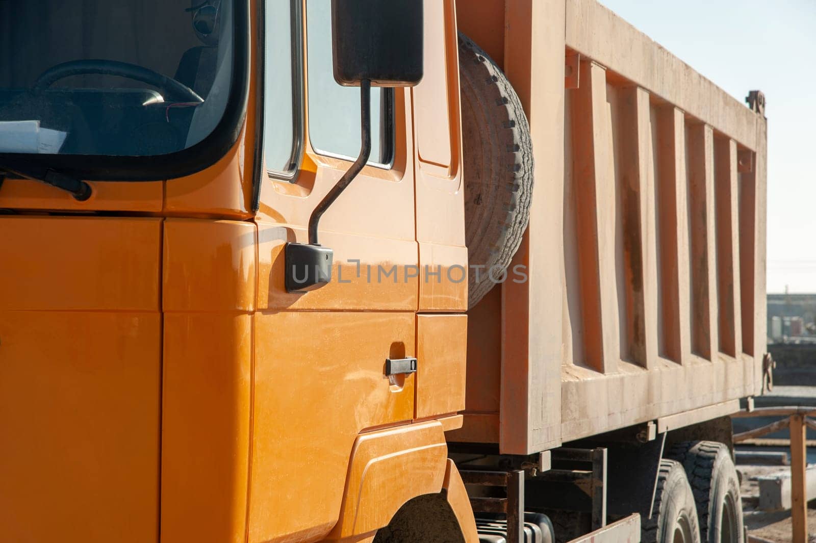 A closeup of an orange dumper truck in an construction area