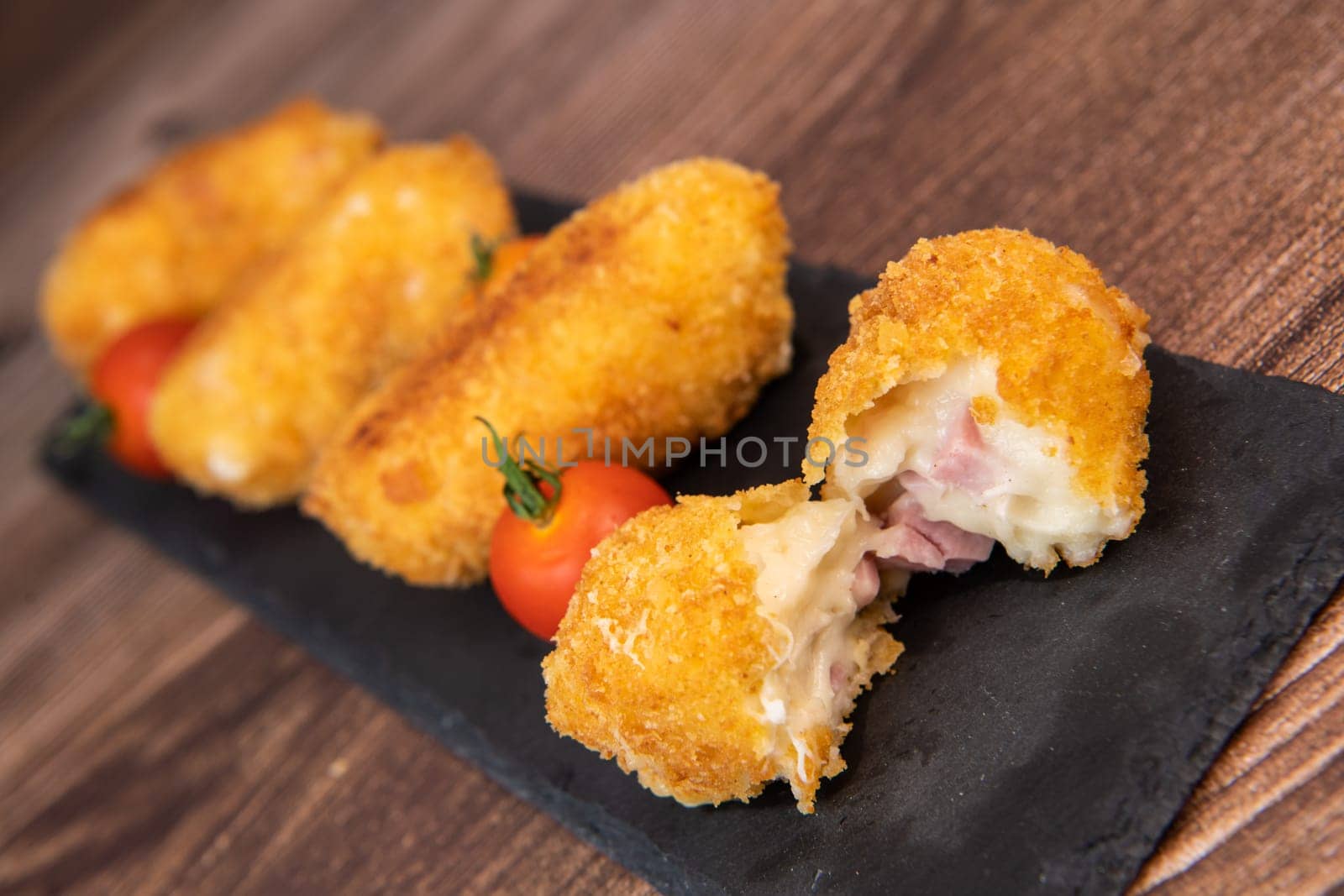 Homemade traditional Spanish croquettes or croquetas on a black plate with fork, Tapas food, High quality photo