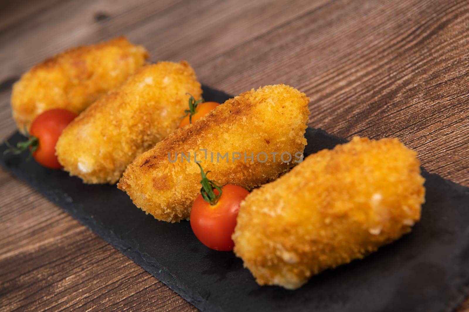 Homemade traditional Spanish croquettes or croquetas on a black plate with fork, Tapas food, High quality photo