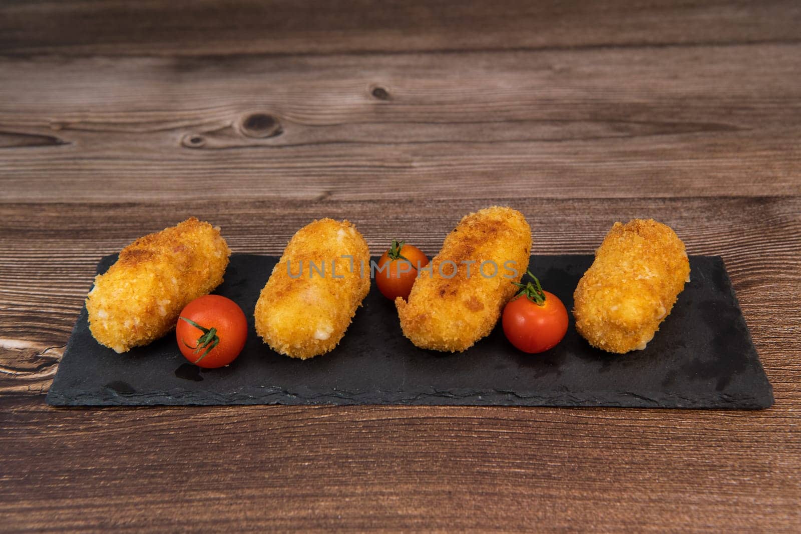 Homemade traditional Spanish croquettes or croquetas on a black plate with fork, Tapas food, High quality photo