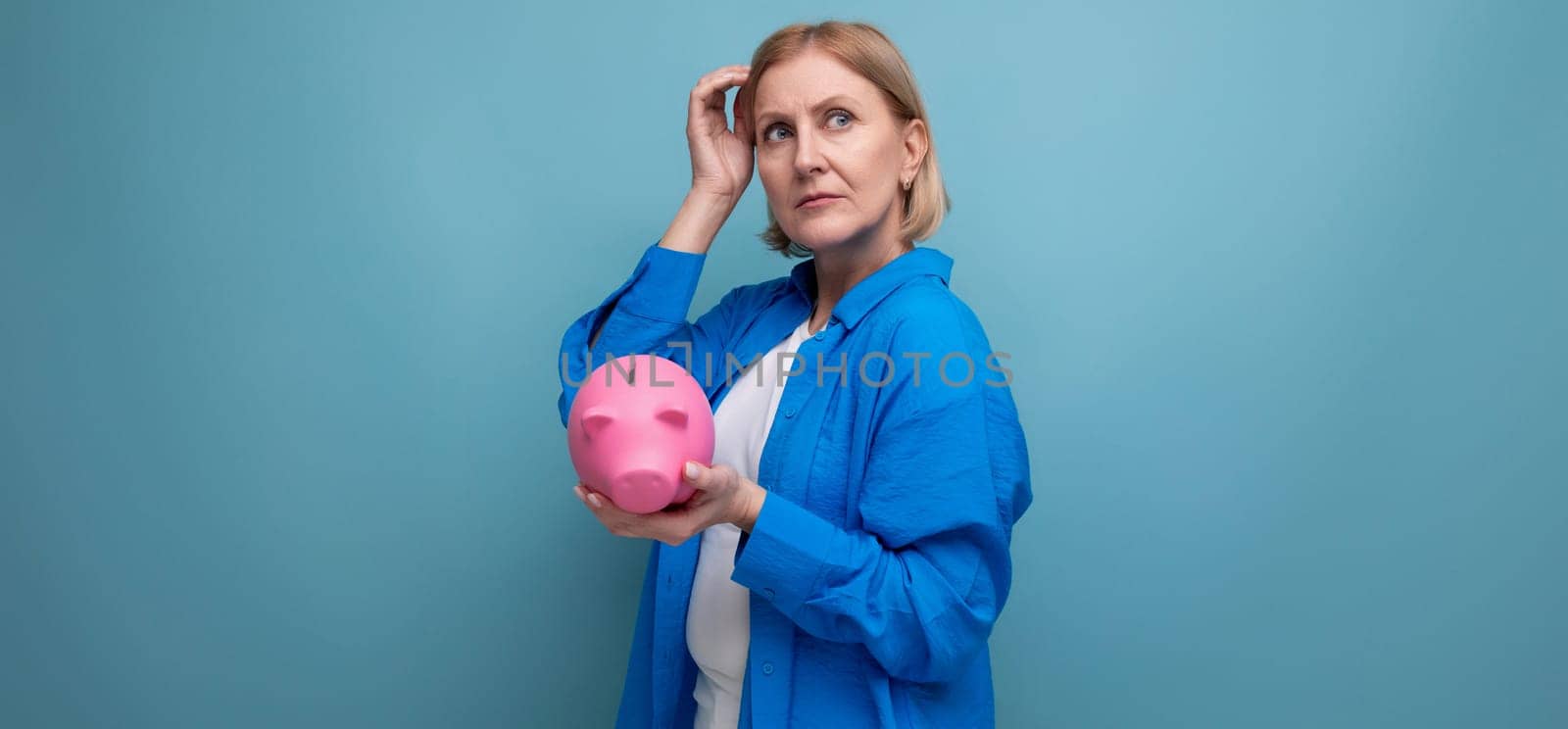 adult woman with a piggy bank of money on a blue background with copy space.