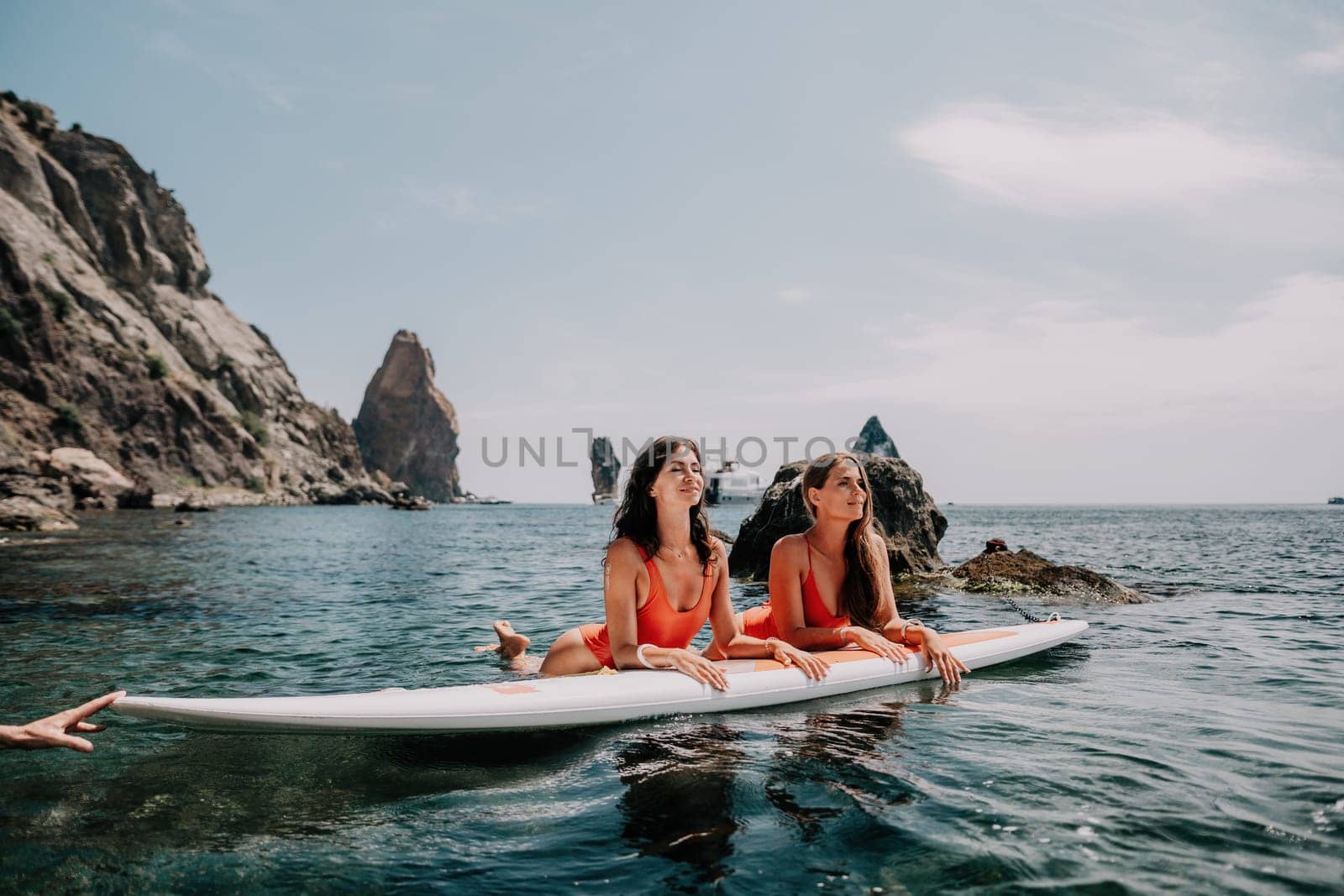 Woman sup yoga. Middle age sporty woman practising yoga pilates on paddle sup surfboard. Female stretching doing workout on sea water. Modern individual hipster outdoor summer sport activity