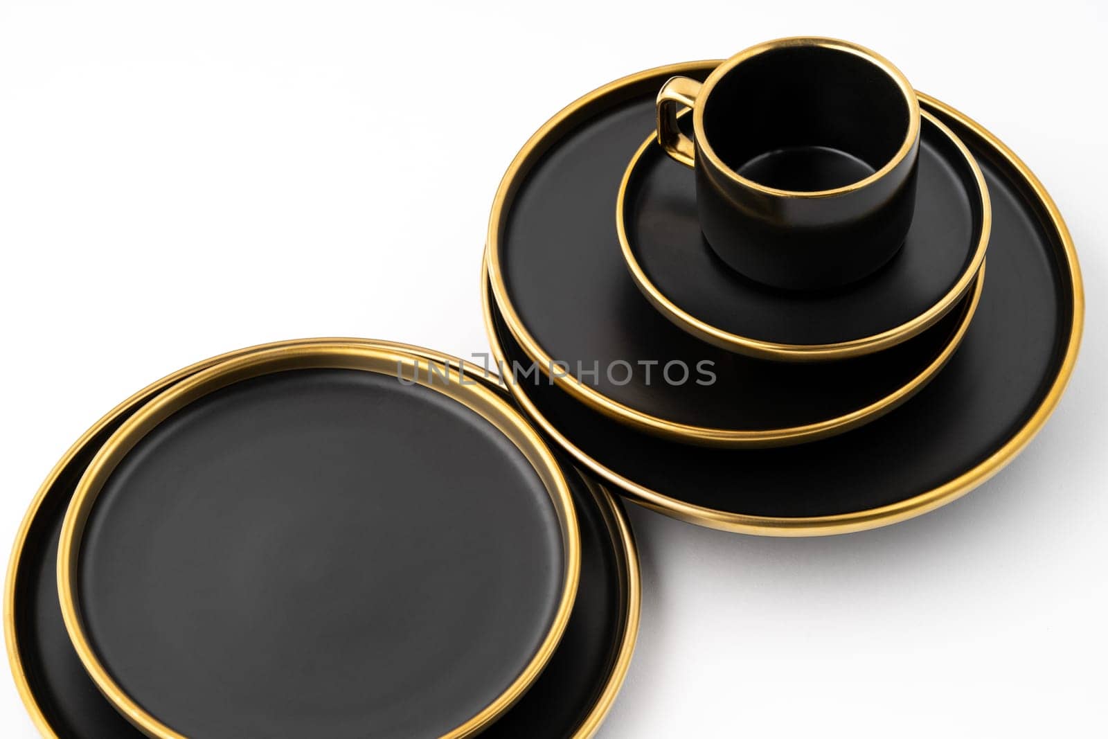 A set of black and golden ceramic plates and cup on a white background