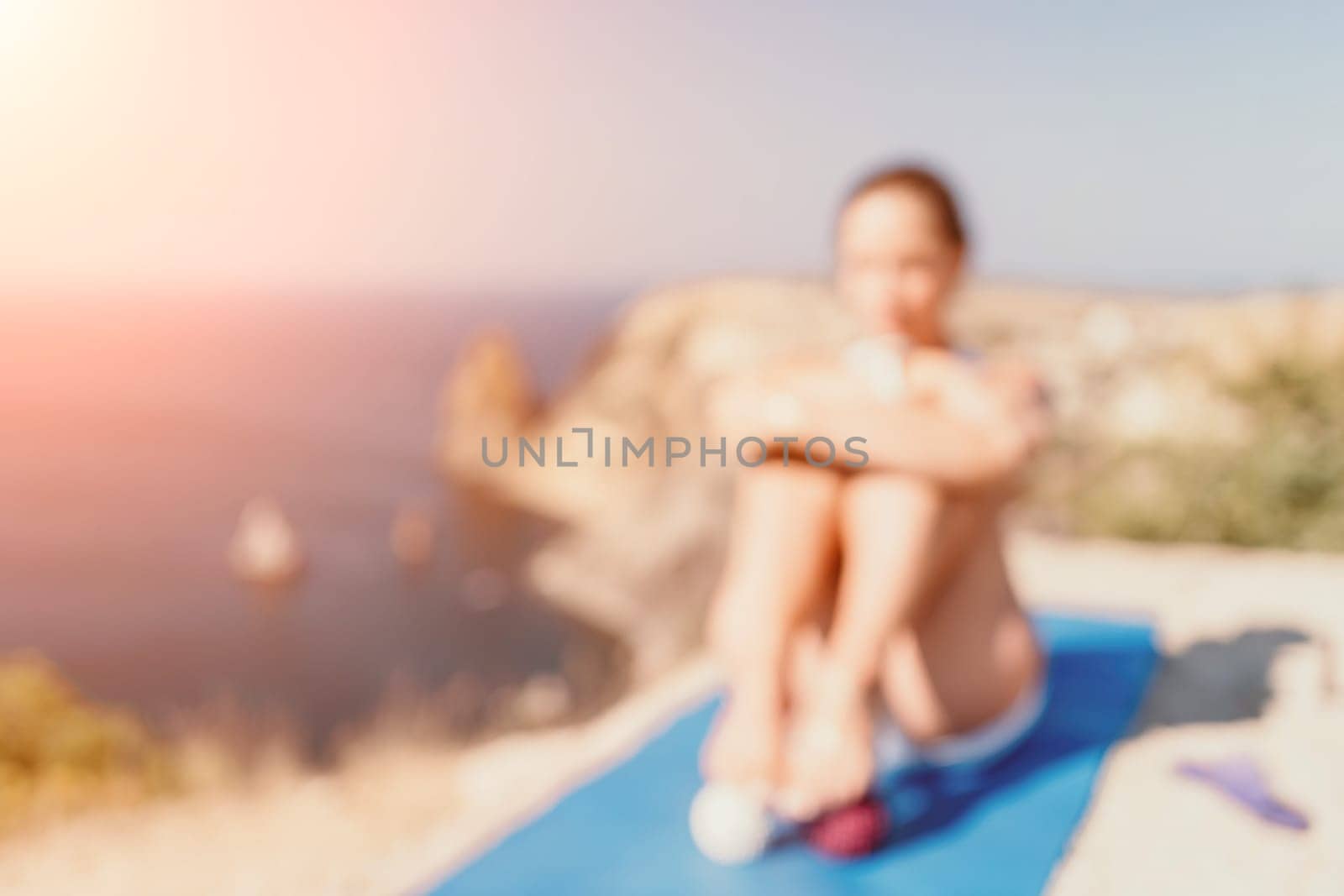 Abstract defocused fitness woman sea. A happy middle aged woman in white sportswear exercises morning outdoors in a park with a beach view. Female fitness pilates yoga routine concept. Healthy lifestyle. by panophotograph