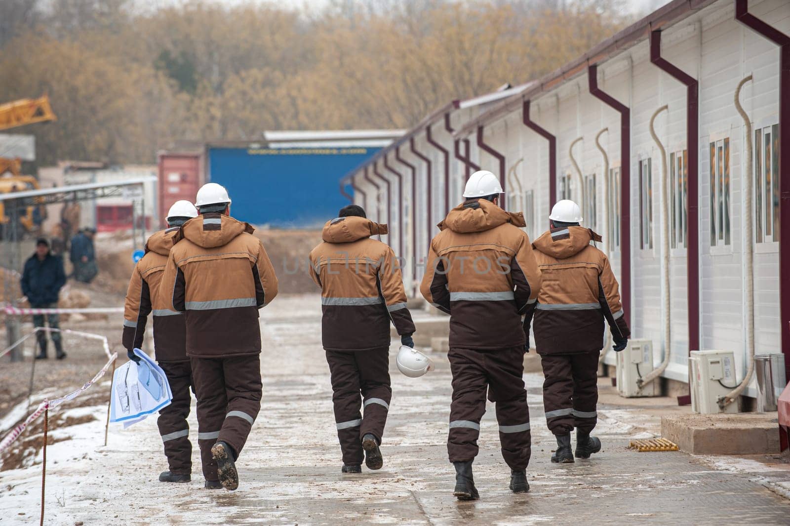 A beautiful shot of workers in special equipment and helmets with oil and gas construction in the background by A_Karim