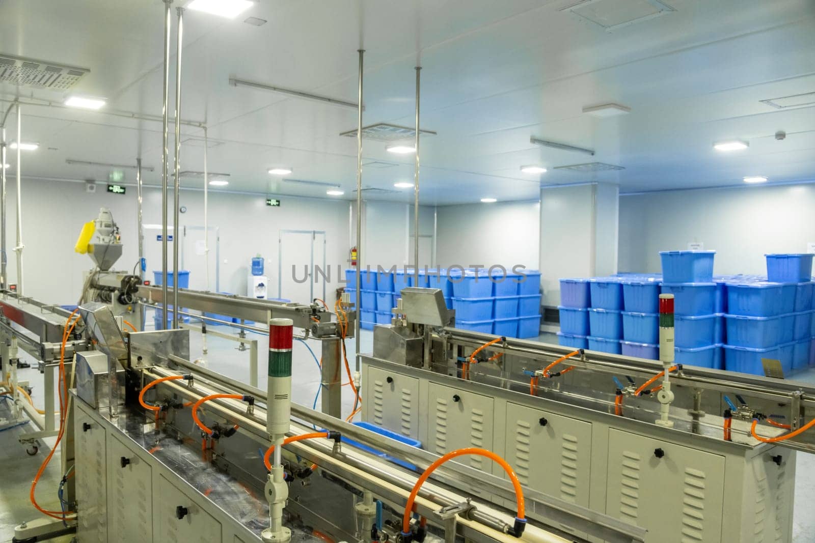 A factory of production of medical syringes and droppers, with equipment and blue containers in the background