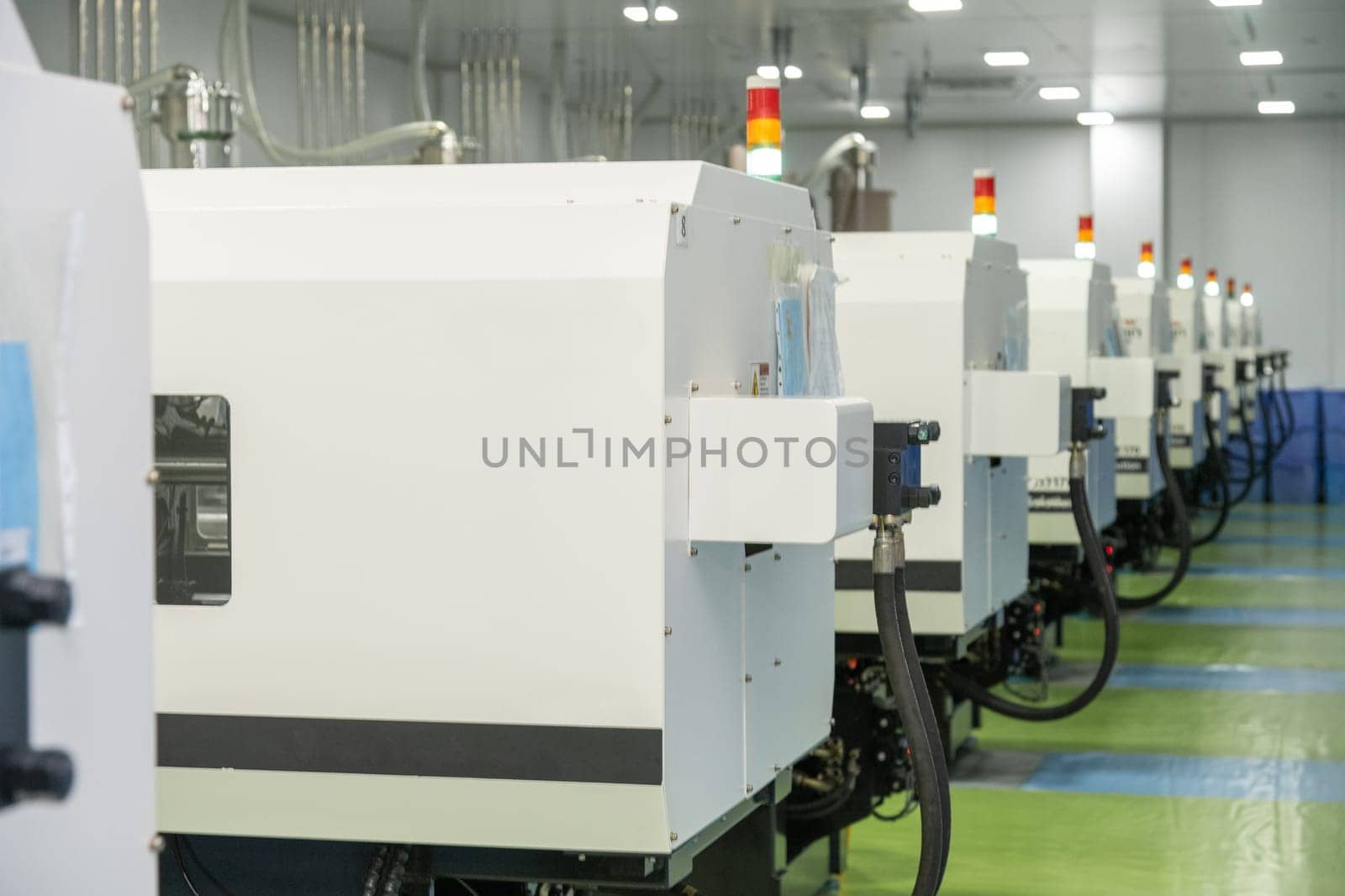 A molding machine from behind with hanging hosepipes in a factory for the production of medical syringes and droppers